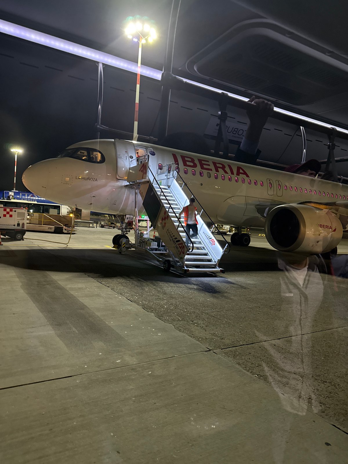 Iberia A320 parked at night on a Milan-area tarmac