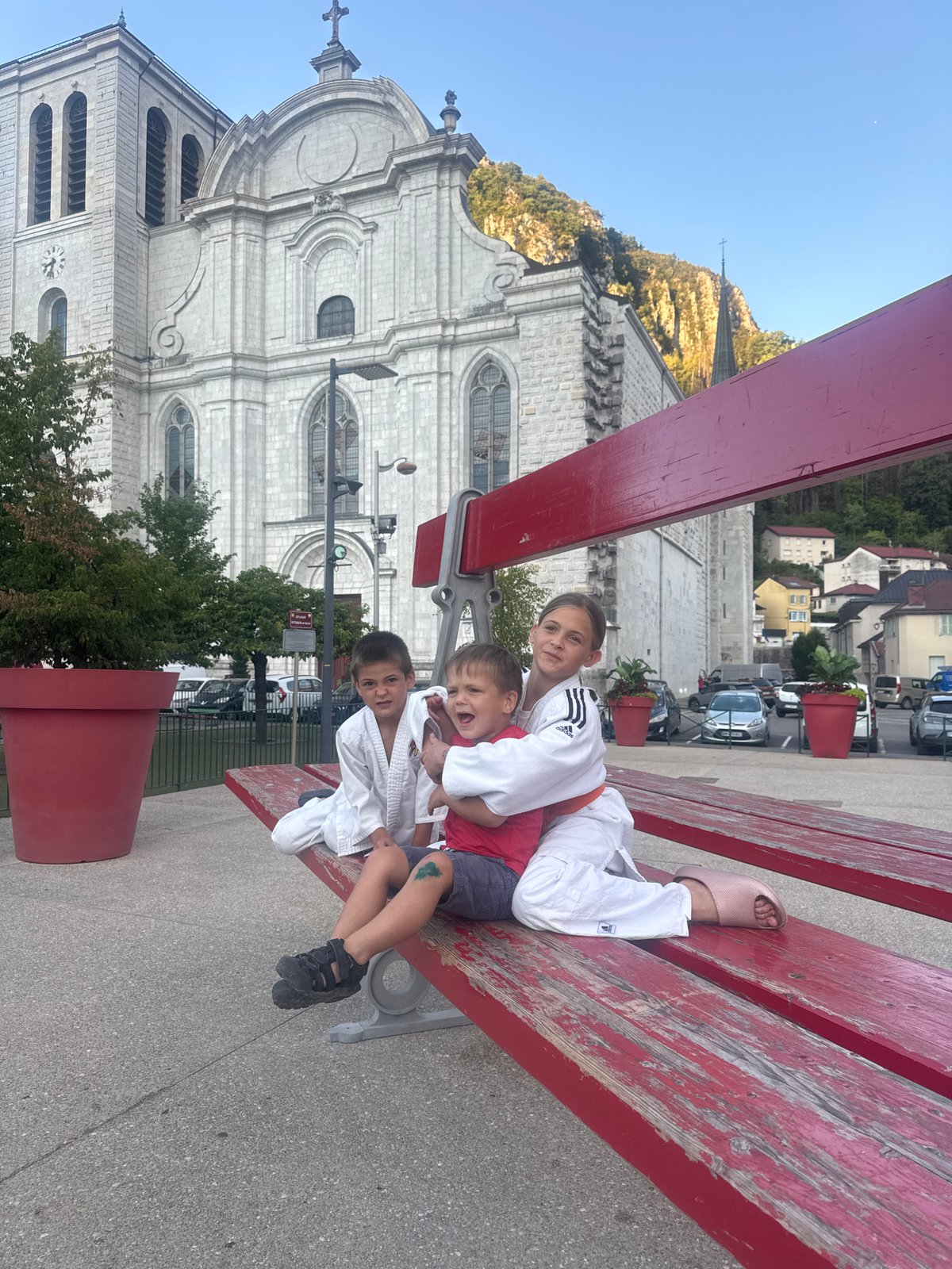 Oversized red bench art installation outside Saint-Claude's historic abbey