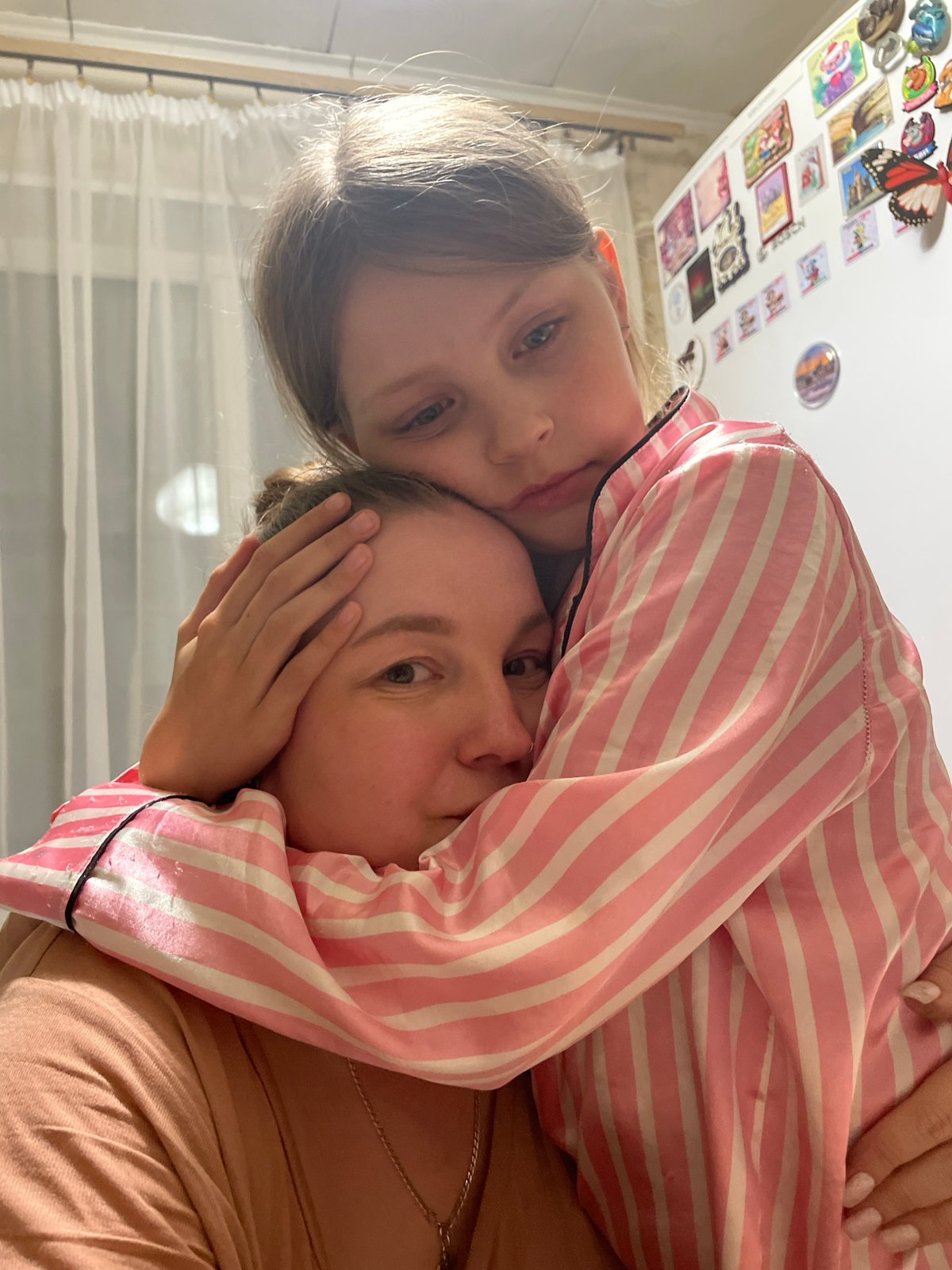 Child in striped pajamas rests on companion's shoulder in Izhevsk