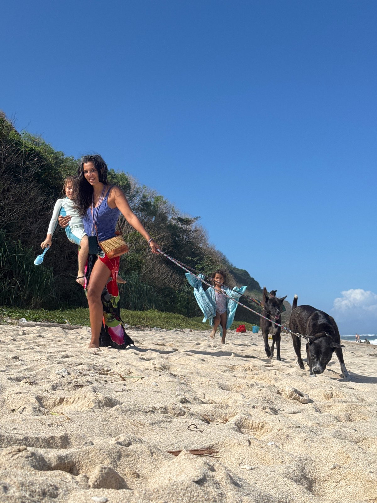 Paragliders, beachgoers, and excavators share a Bali morning shore