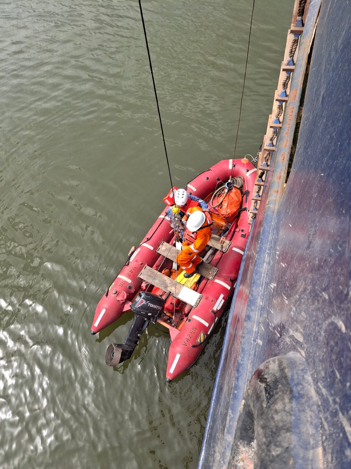 Maritime workers conduct boat operations near cargo ship