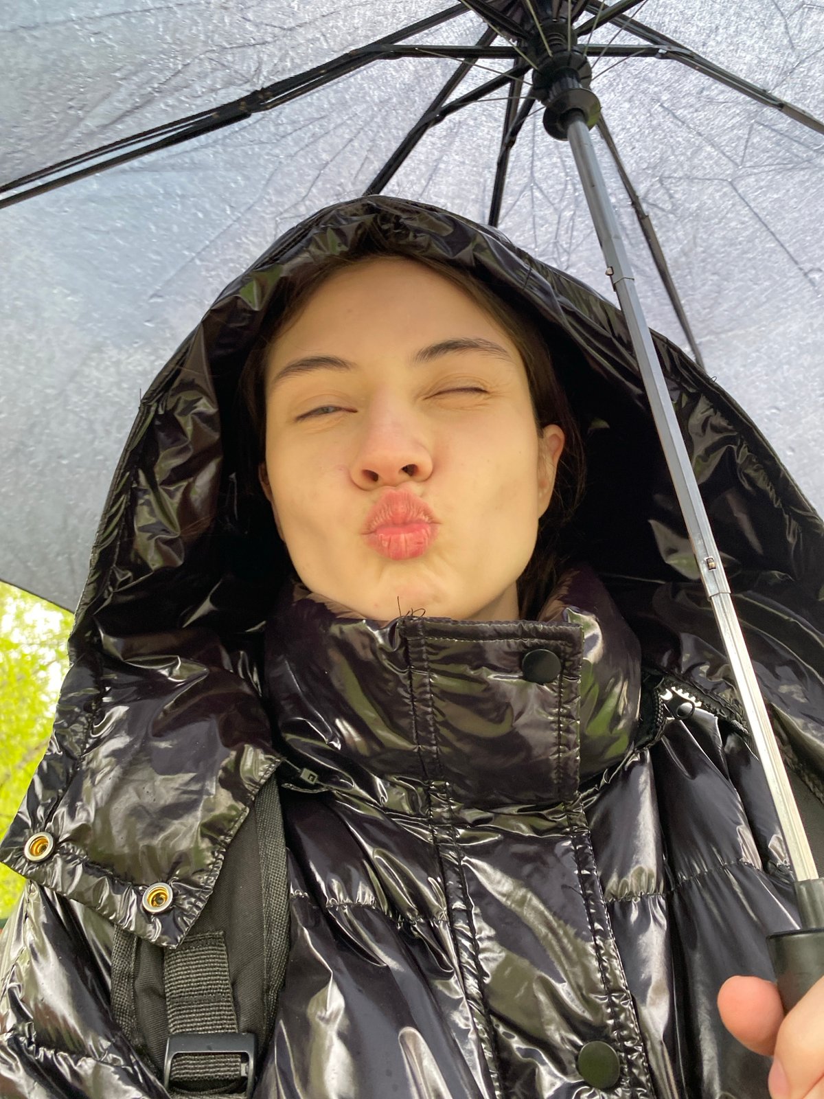 Woman poses playfully with umbrella on rainy Votkinsk street
