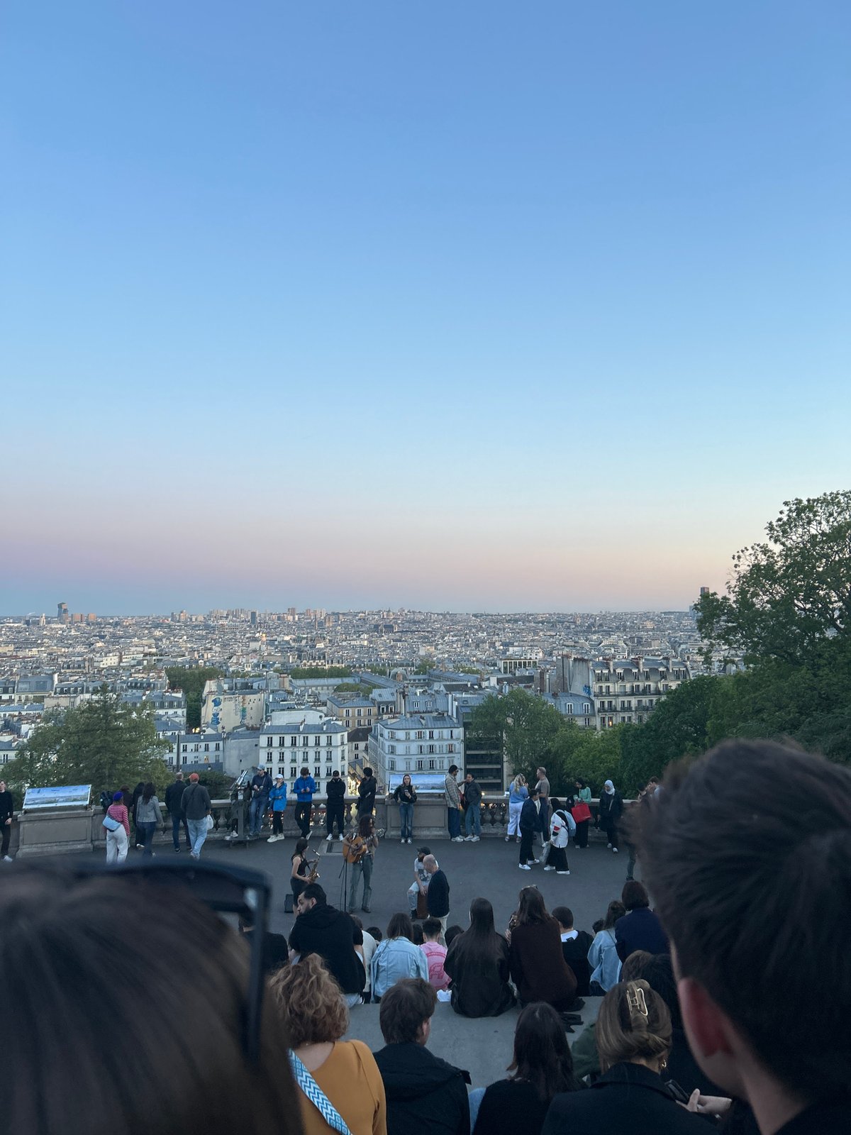 Crowd gathers for music performance overlooking Paris at dusk