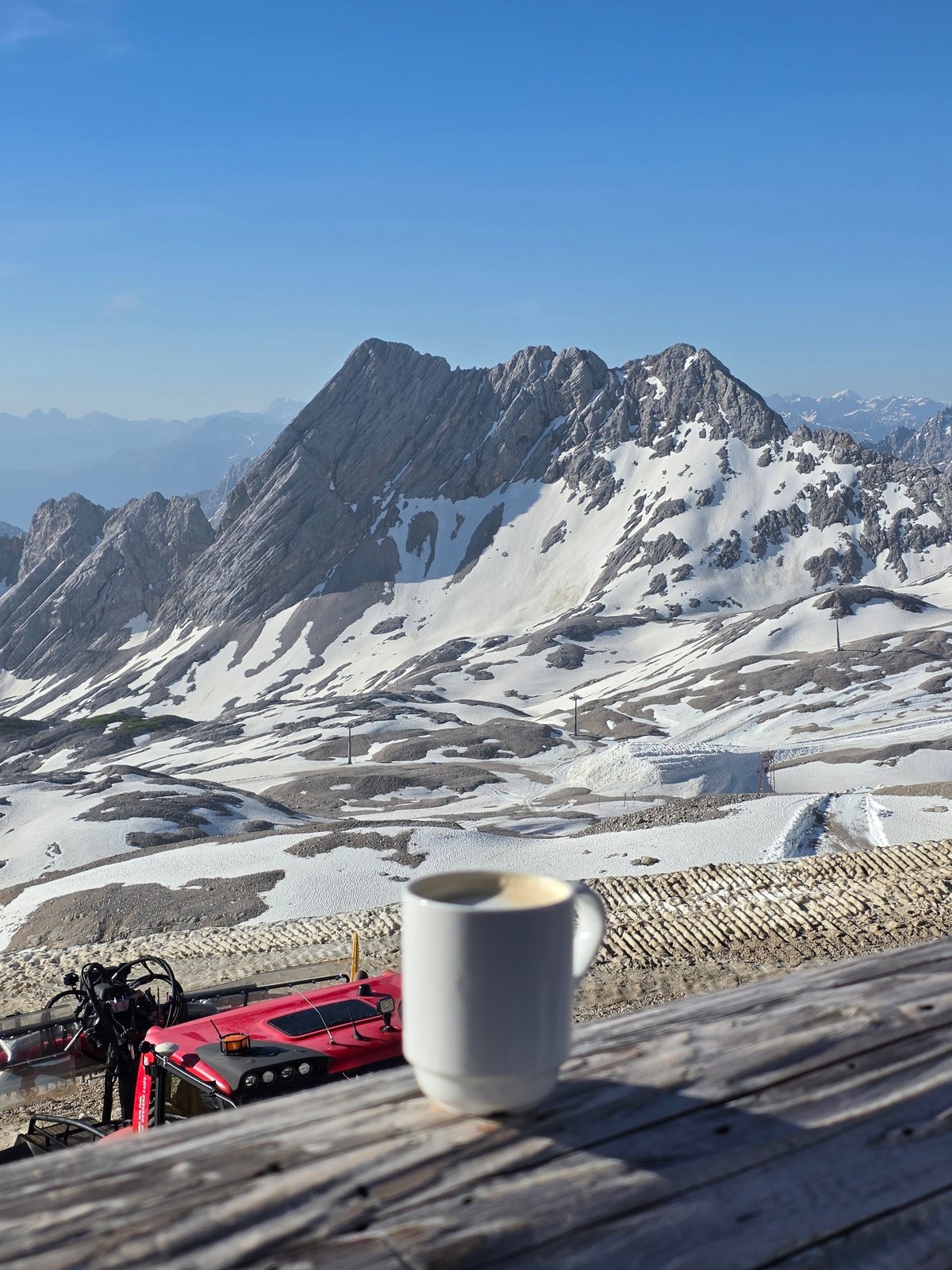 Coffee and snow groomers on the Zugspitze on a clear June morning