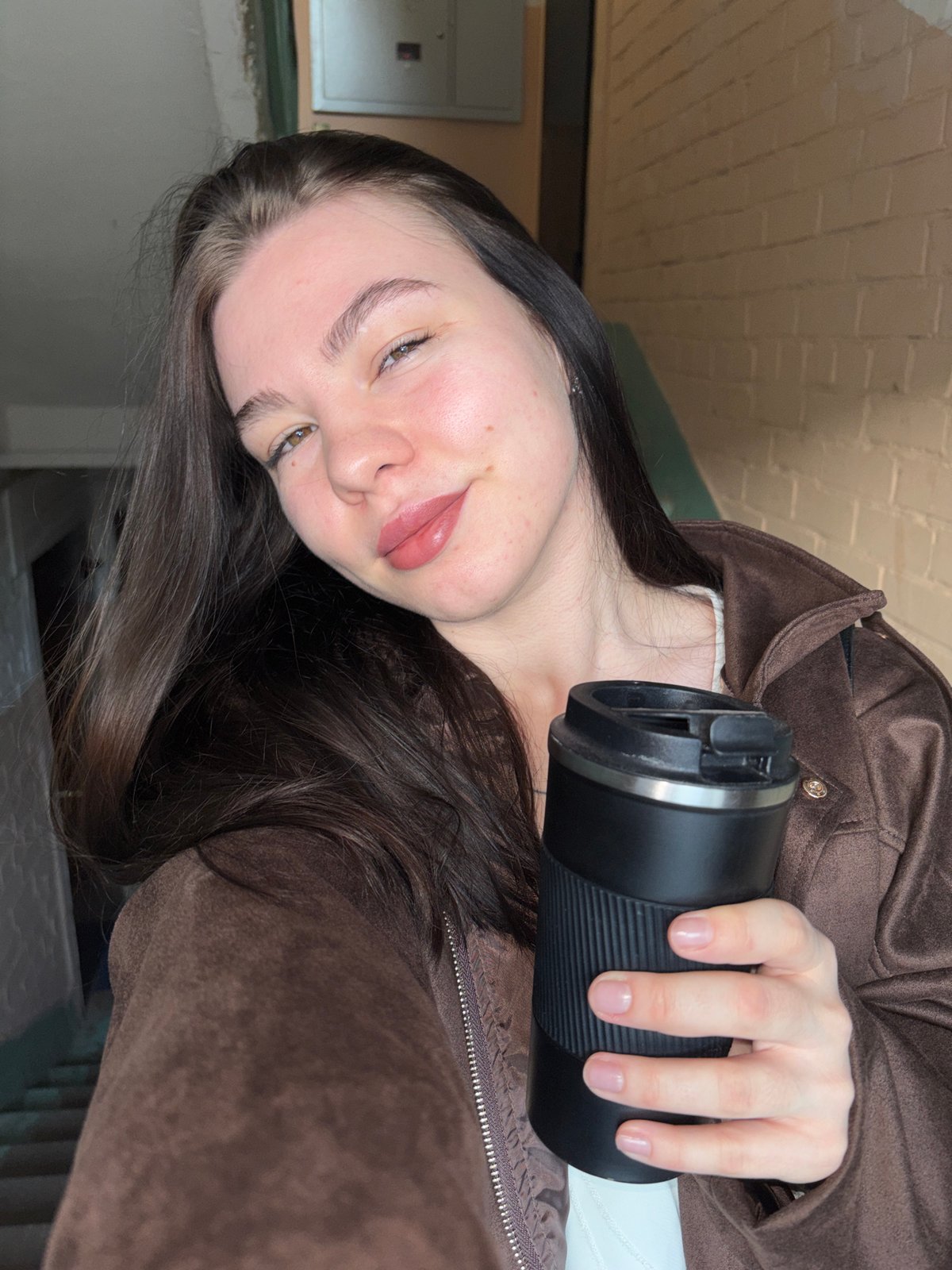 Woman takes indoor selfie with travel mug in Perm