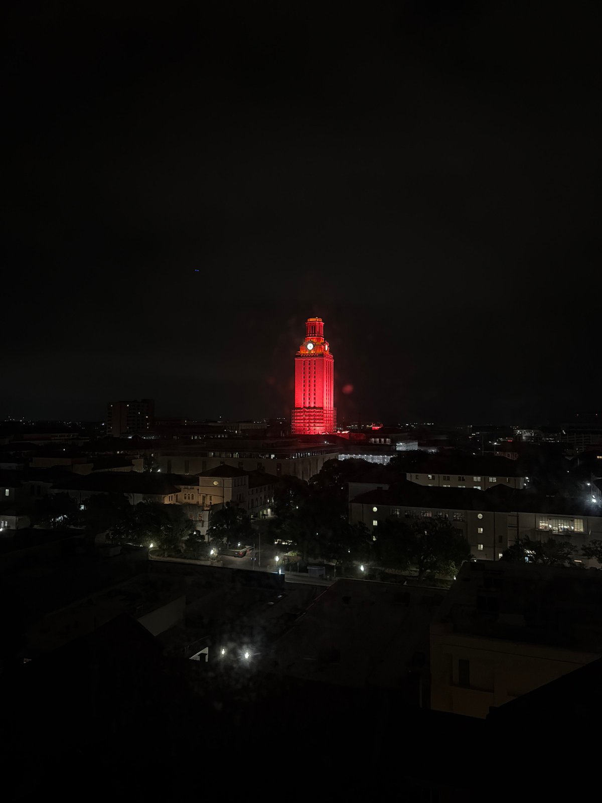 UT Tower glows red in Austin nighttime cityscape