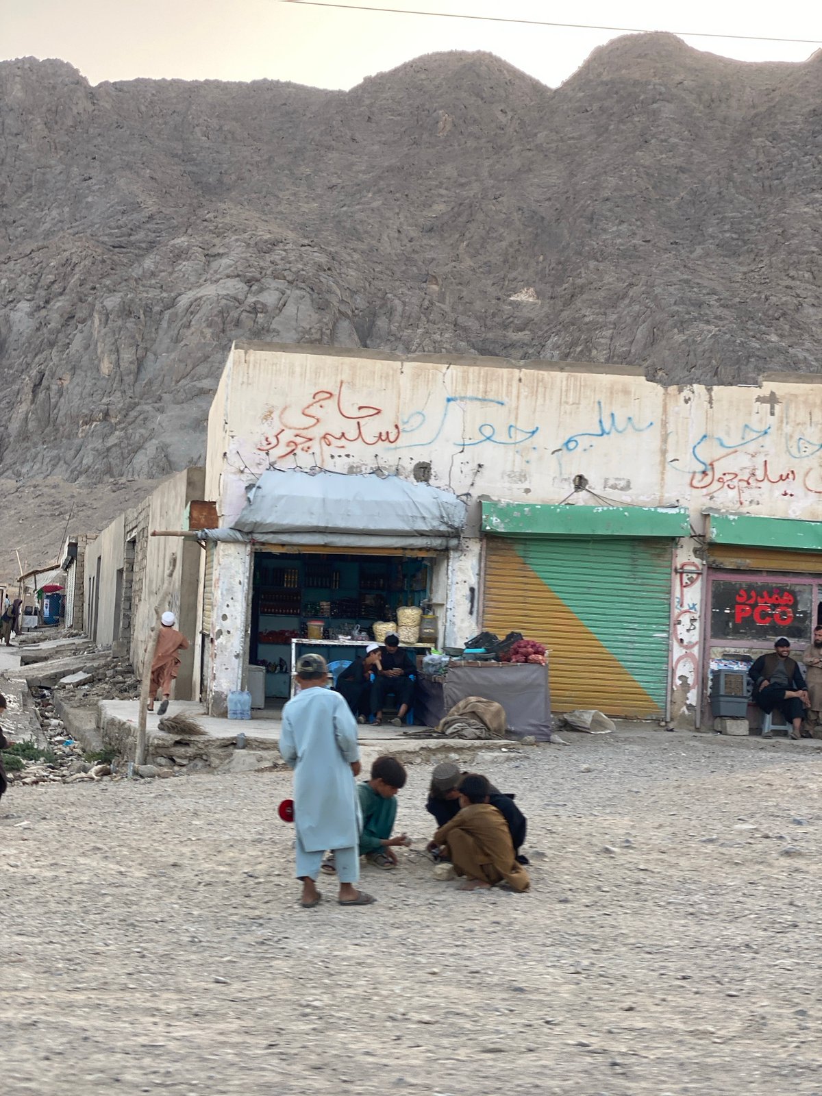 Unpaved street scene amid Kandahar's rugged mountain backdrop