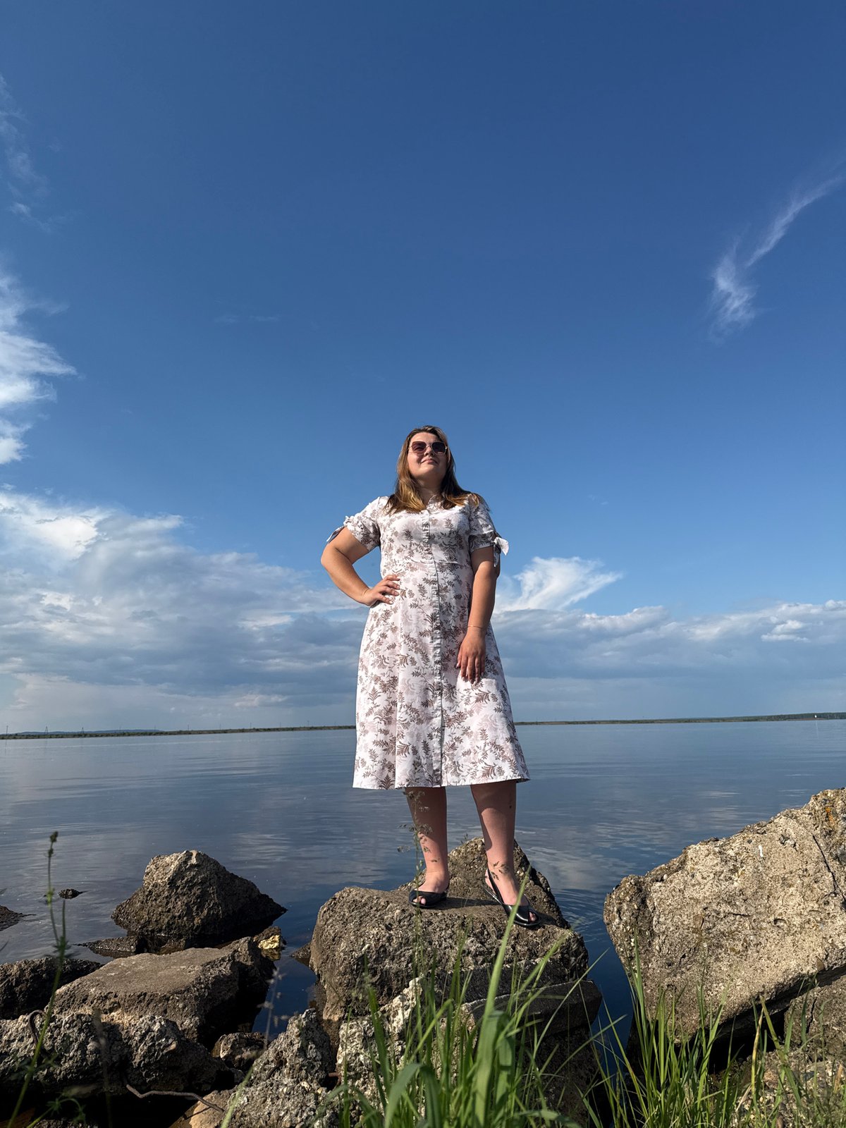 Woman poses by water under dramatic sky in Chaikovsky