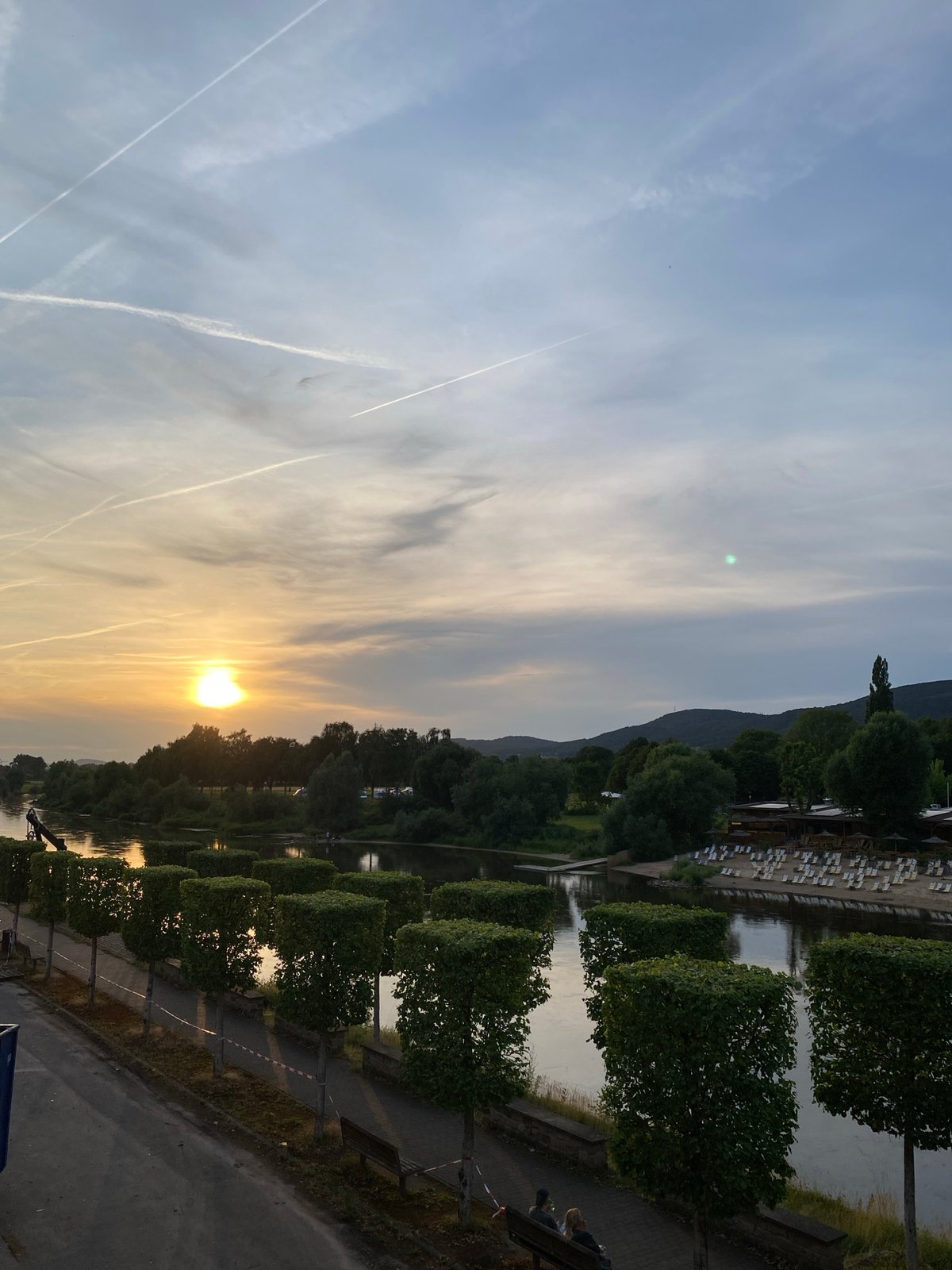 Golden sunset and contrail-filled skies over the Weser River
