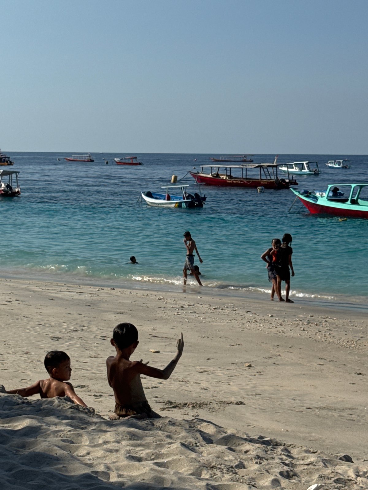 Thatched bar, boats, and turquoise water on an Indonesian beach