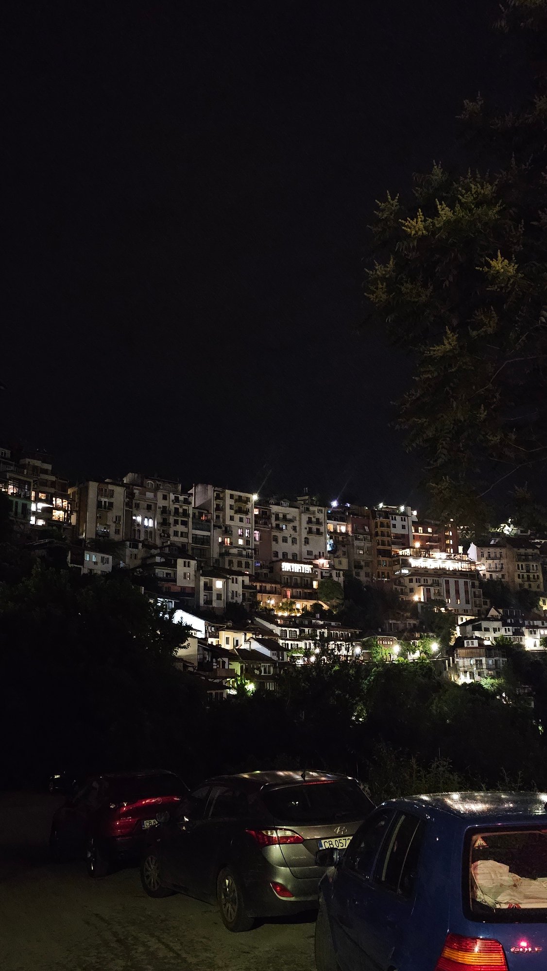 Nighttime urban hillside scene documented with illuminated buildings