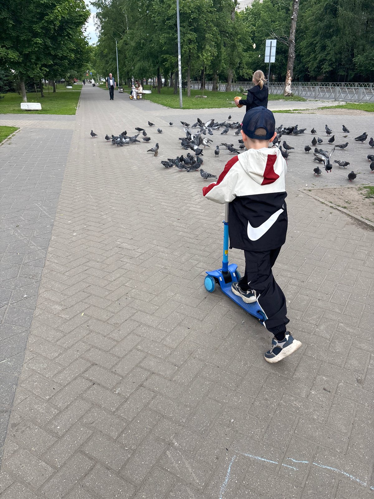 Child with Patriots cap plays with scooter in Russian park