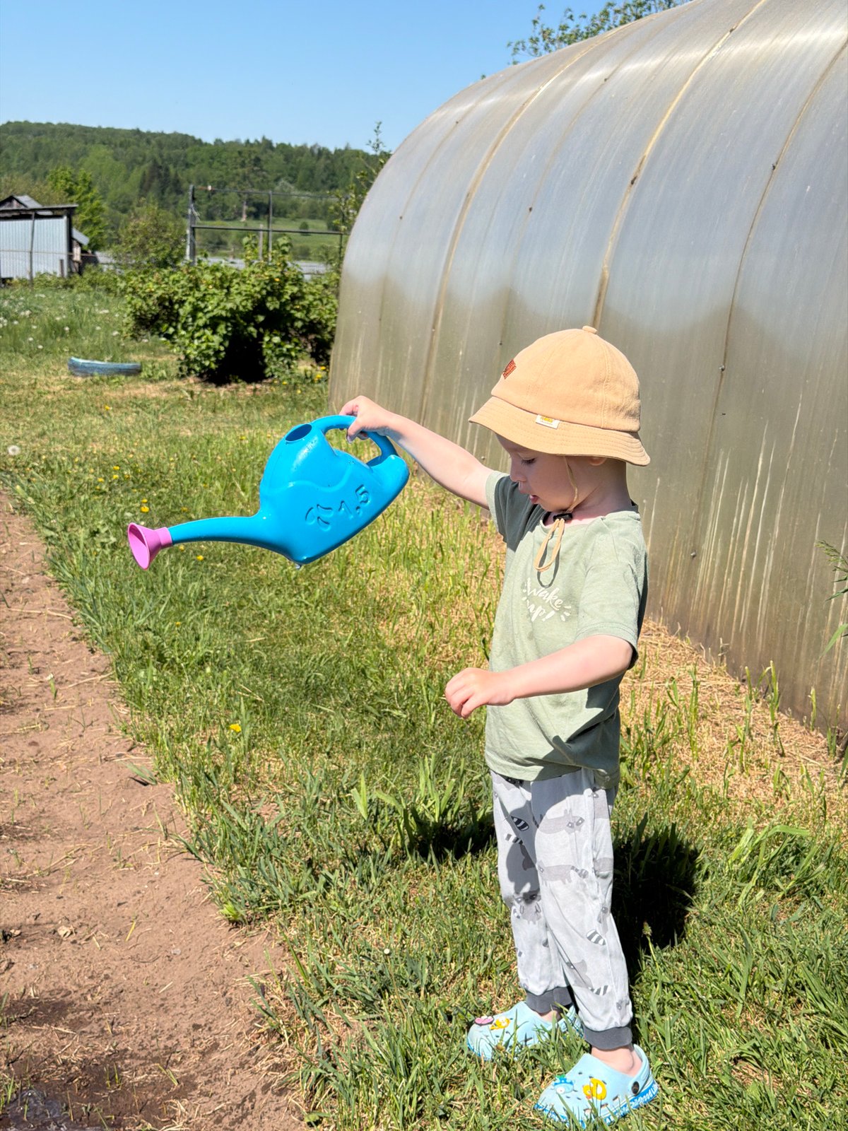 Child gardens and plays with water in Russian village