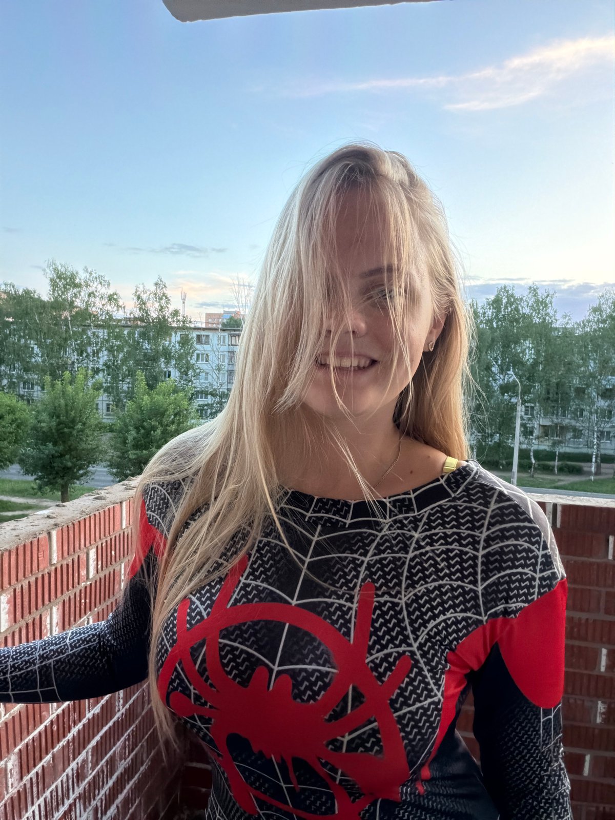 Woman poses in Spider-Man costume on Izhevsk balcony at sunset