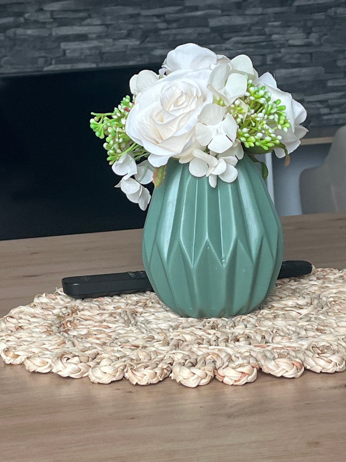 Green geometric vase and white flowers on a wooden table