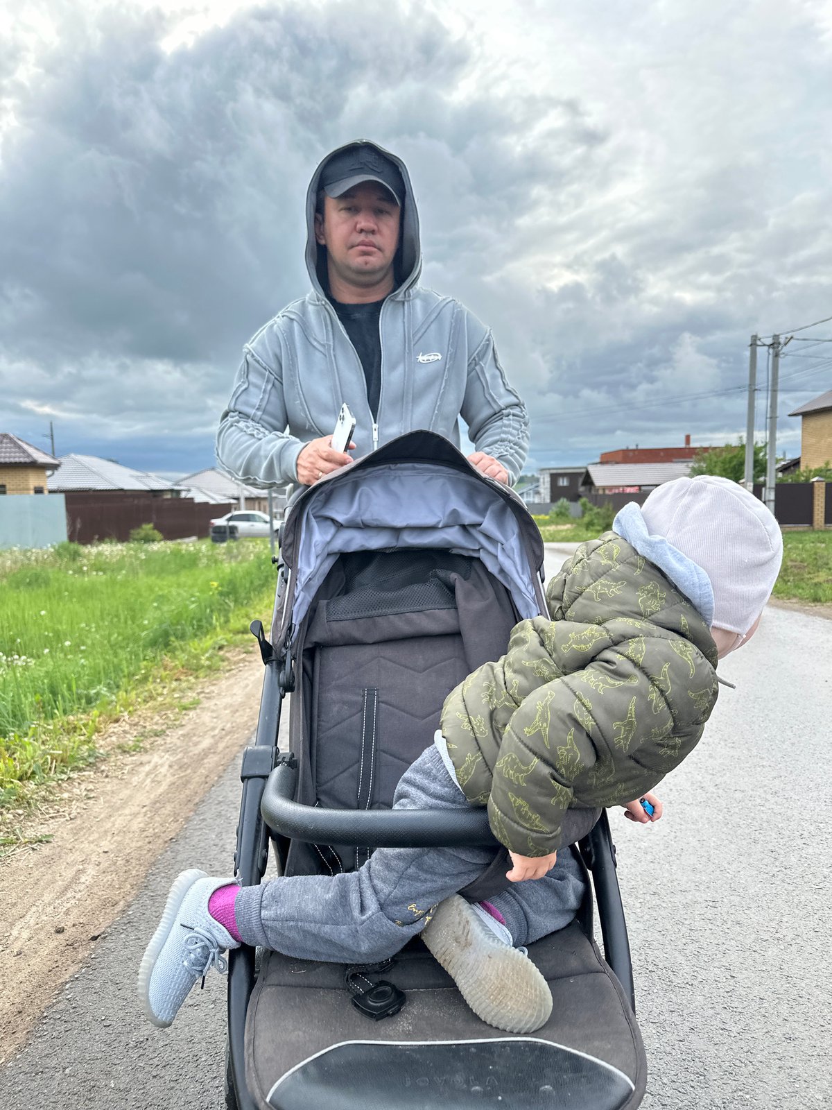 Father pushes stroller through wet streets in Éstachi, Russia