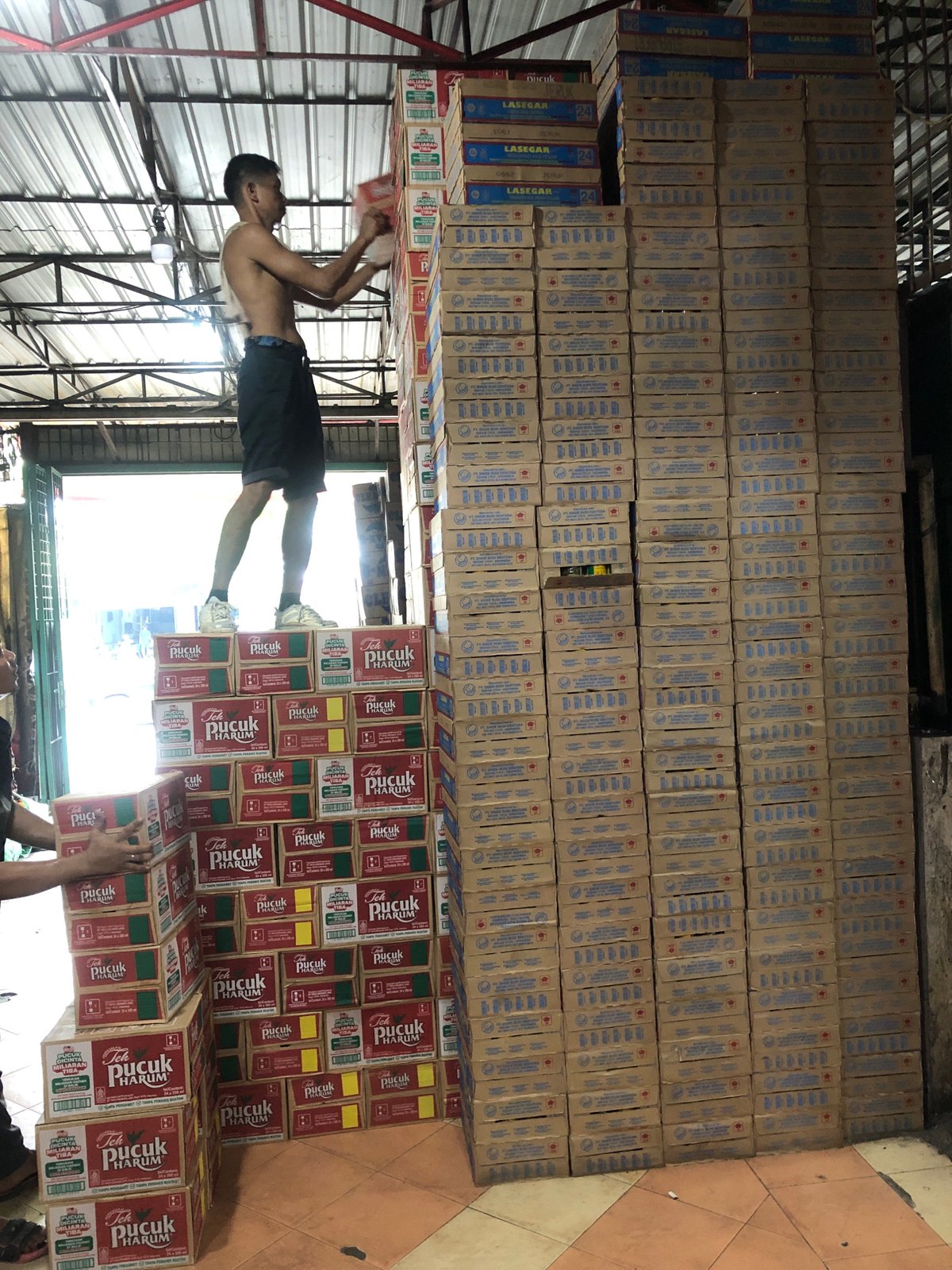Workers handle beverage inventory in Medan warehouse facility