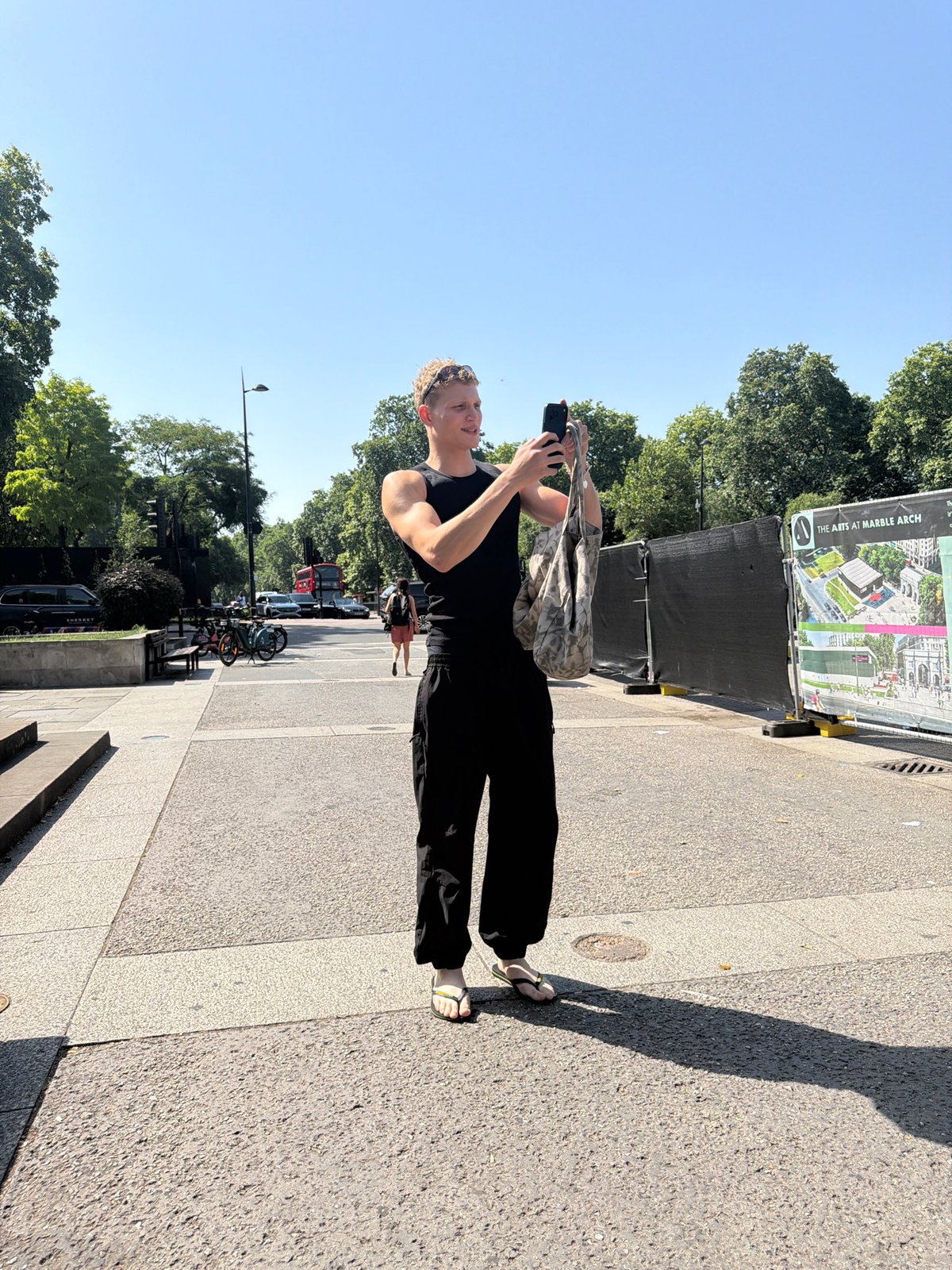 Phone in hand beside a grand London archway on a sunny morning