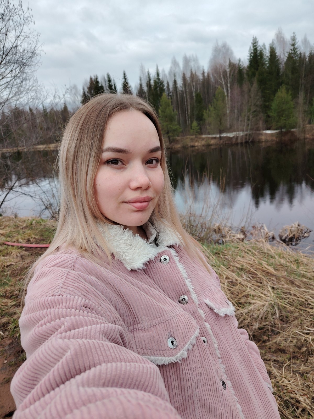 Woman takes selfie by reflective lake in Chaikovsky, Russia