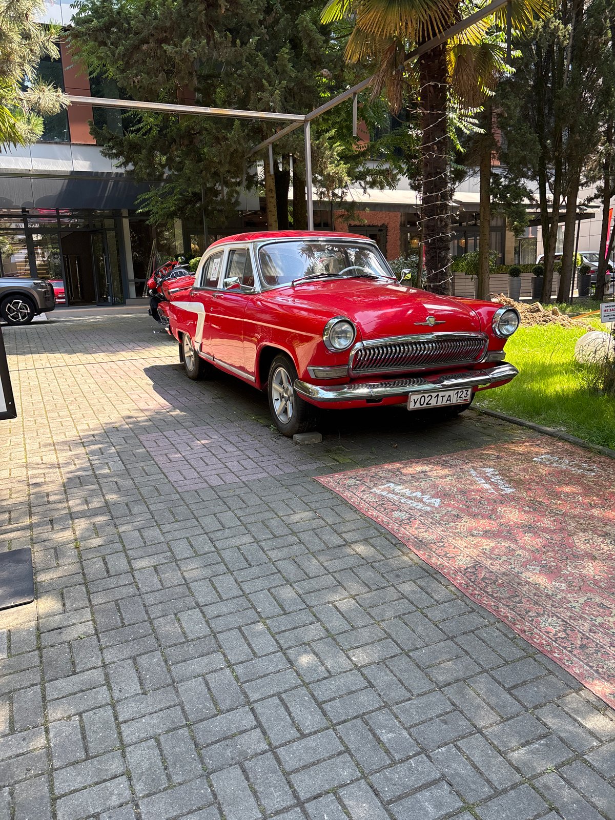 Sochi street life centers on a parked vintage Volga and busy sidewalks.