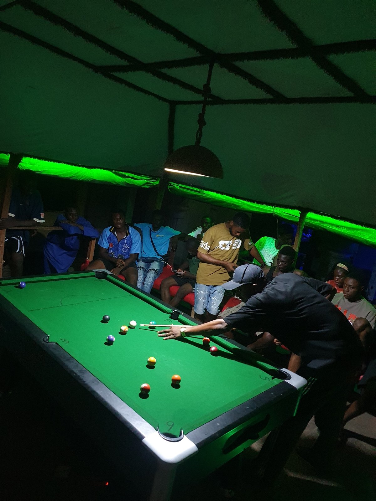 Young men play pool at nighttime venue in Lokoja