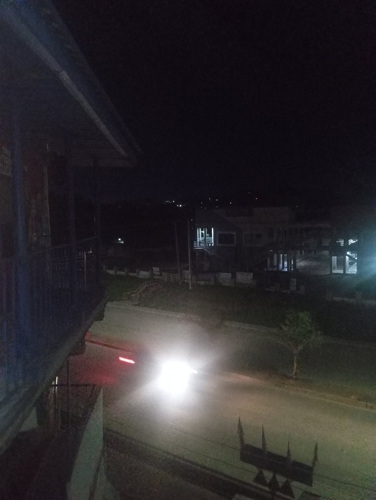 Vehicle travels nighttime street near illuminated modern building