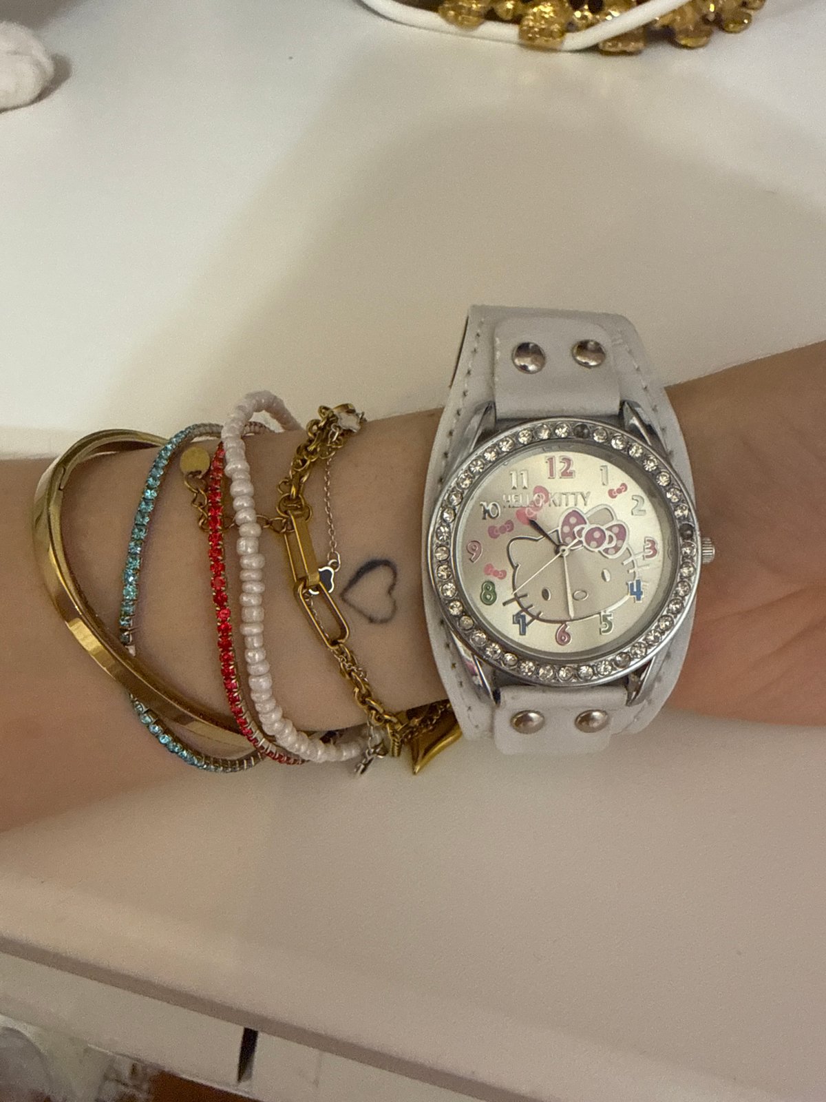 Hello Kitty watch and stacked bracelets, cat in the background