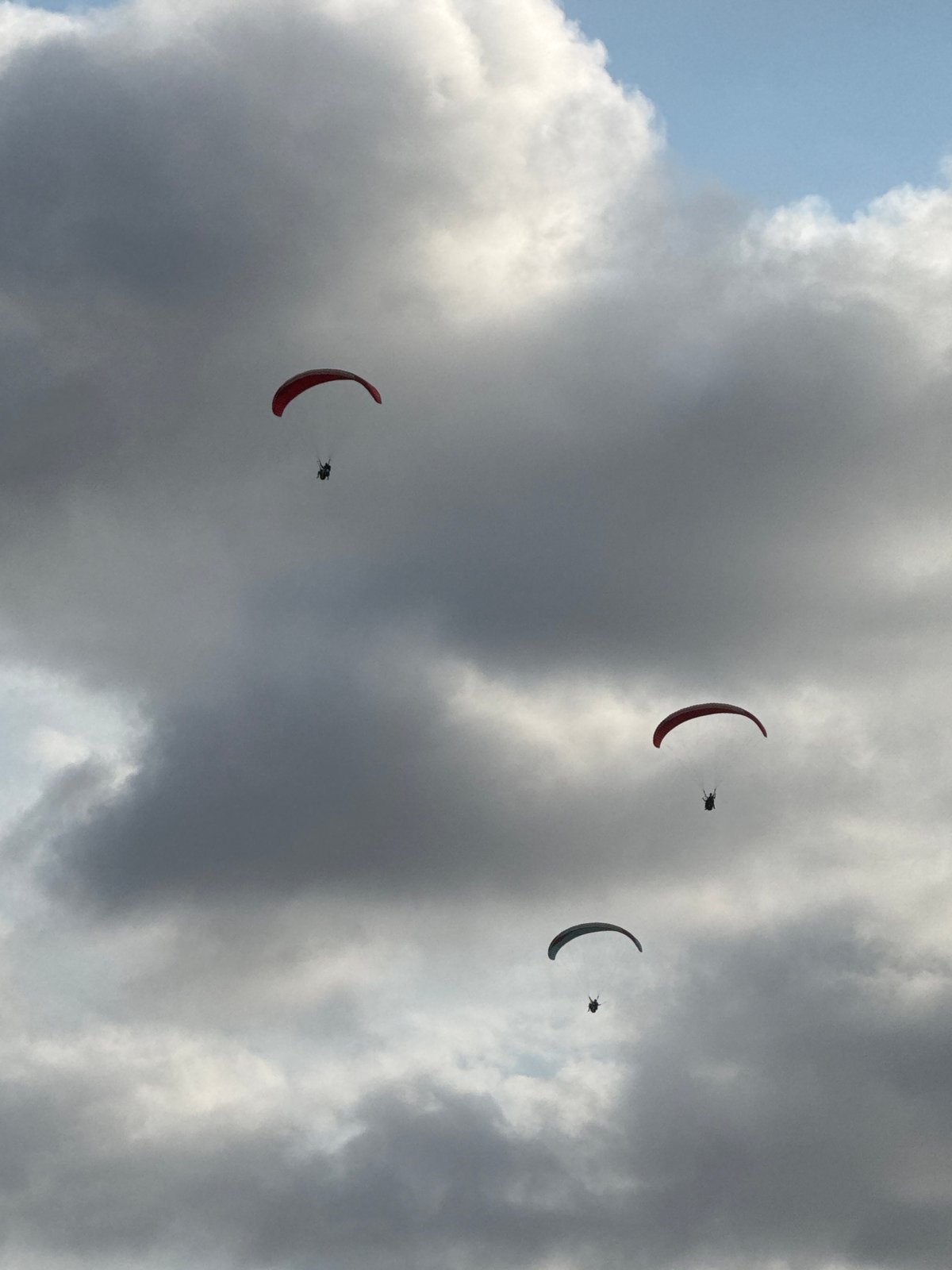 Paragliders, paddlers, and beachgoers fill a Bali coastal morning