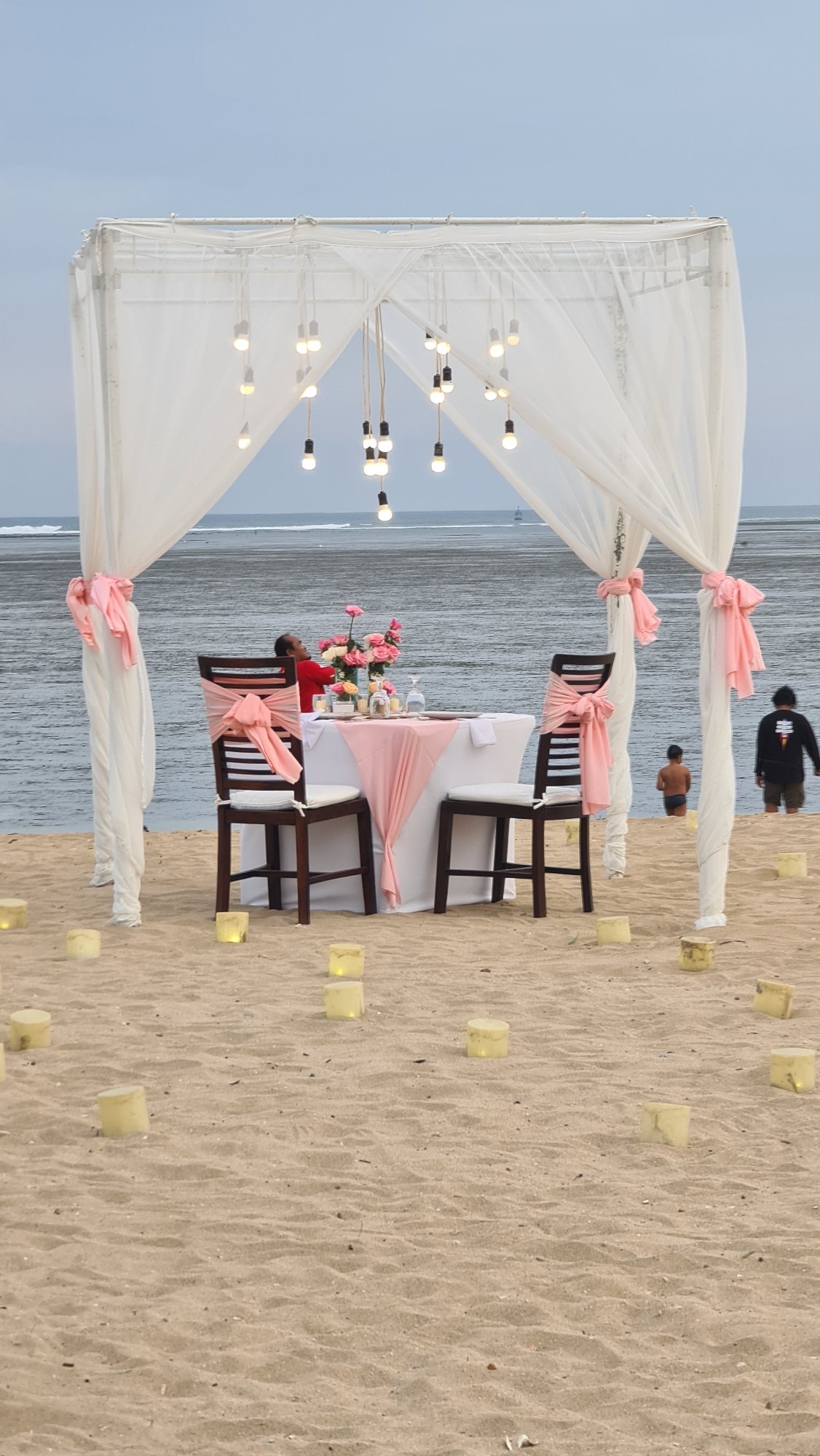 Quiet morning on a Denpasar beach: dining setups, boats, and joggers