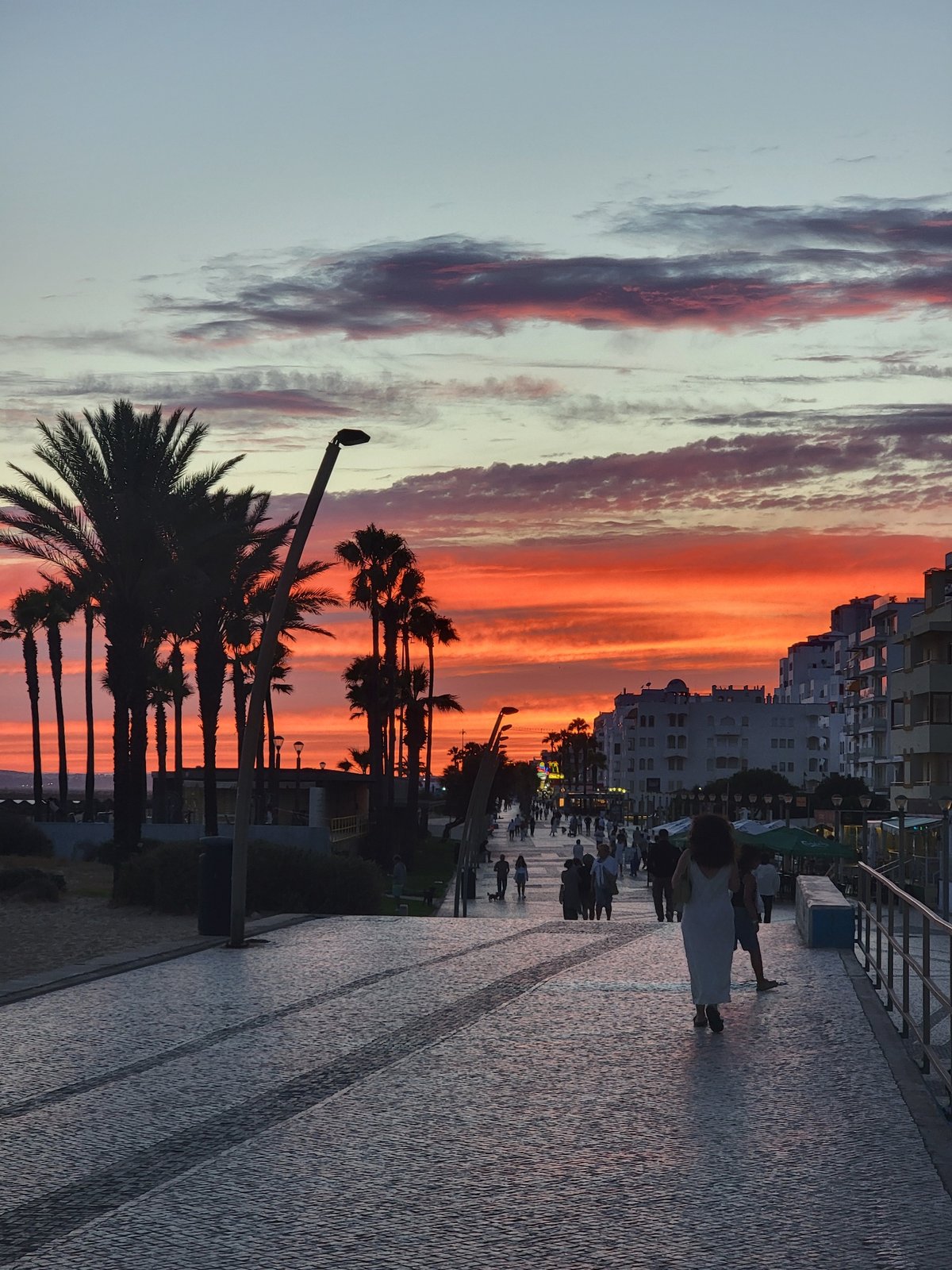 Quarteira promenade fills up during a vivid Atlantic sunset
