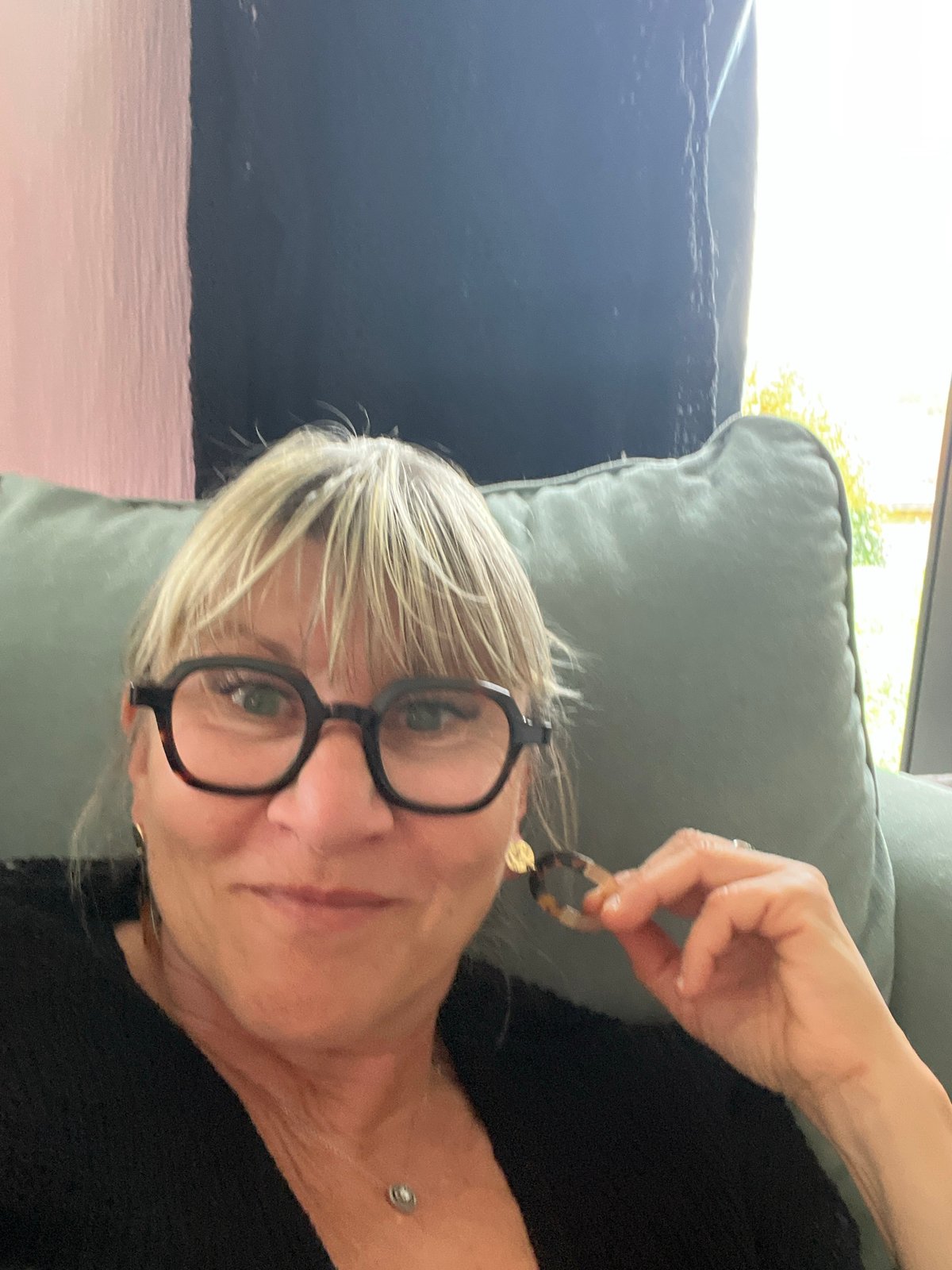 Woman displays tortoiseshell earrings indoors in Chambœuf