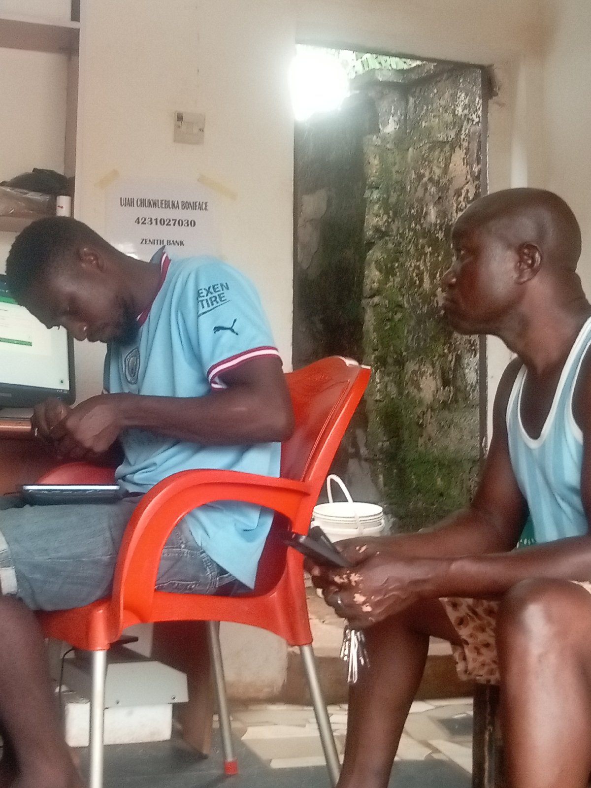 Two men spotted indoors in Ogidi, one using tablet