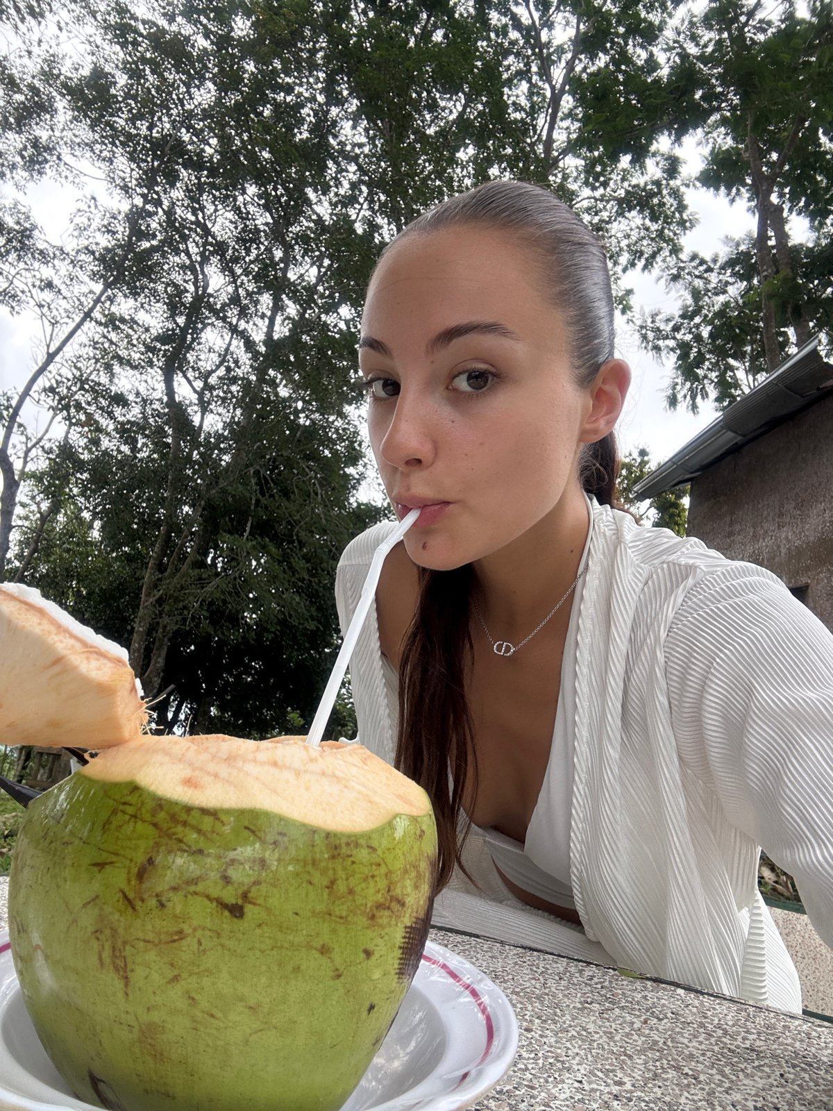 Woman enjoys coconut drink at beachside café in Karon