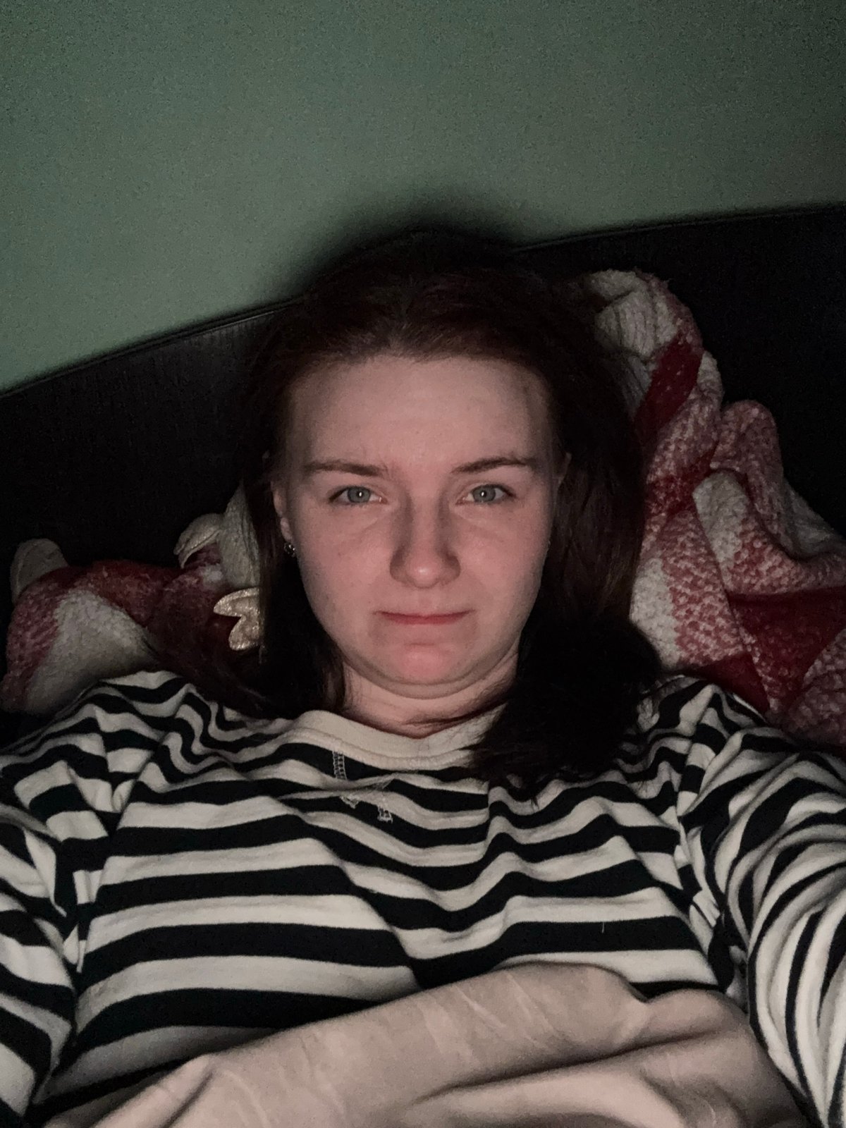 Woman rests indoors wearing striped shirt, location unknown