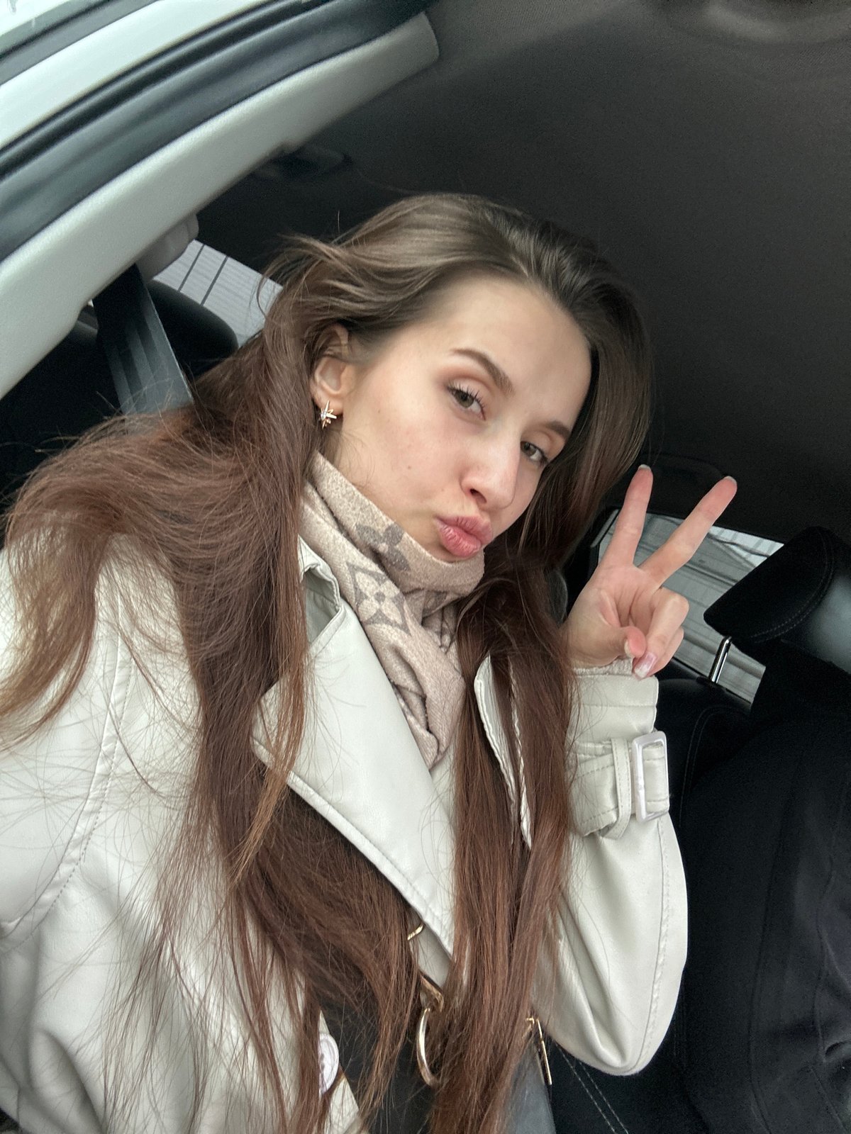 Woman makes peace sign gesture in vehicle in Chaikovsky