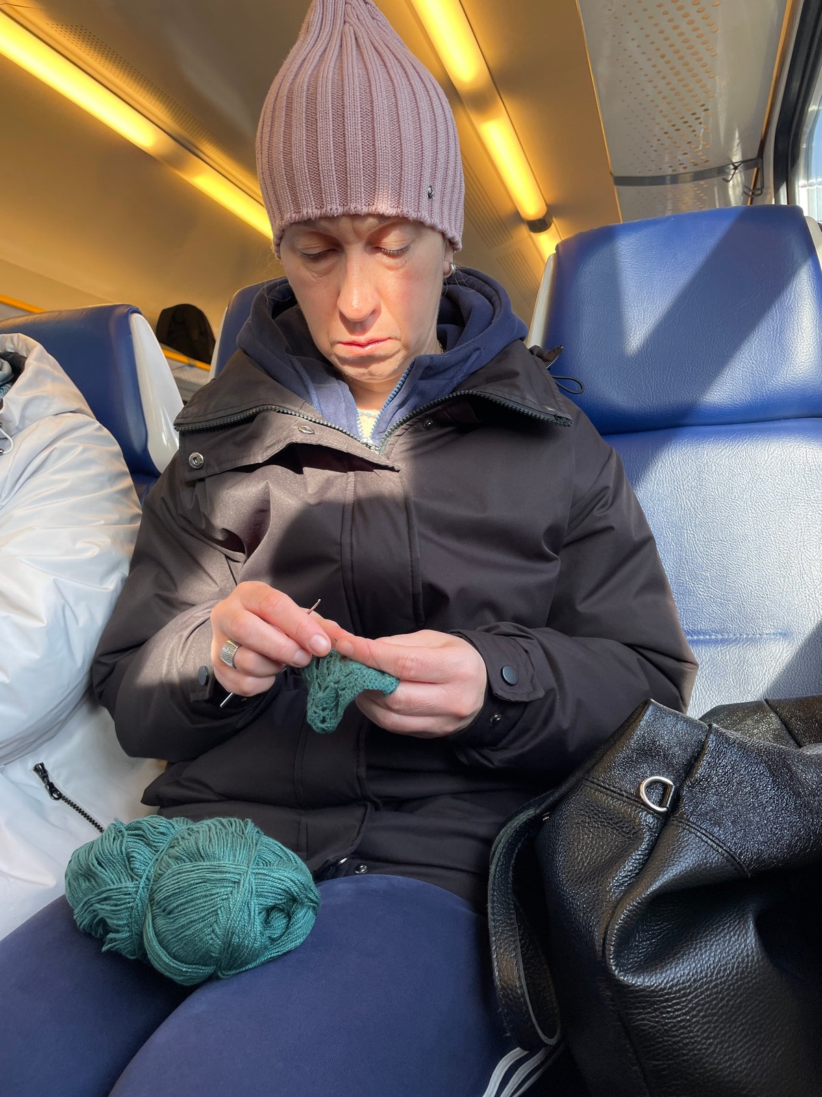 Train passenger knits during early morning journey in Balashikha