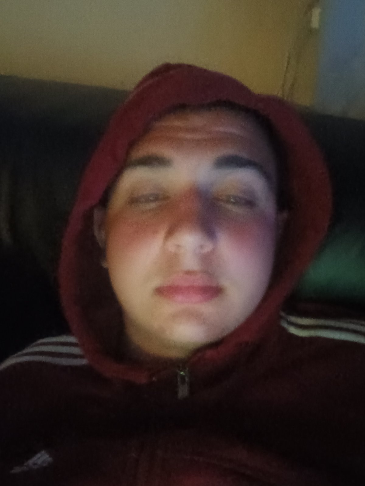 Person in Adidas hoodie rests on couch while using phone