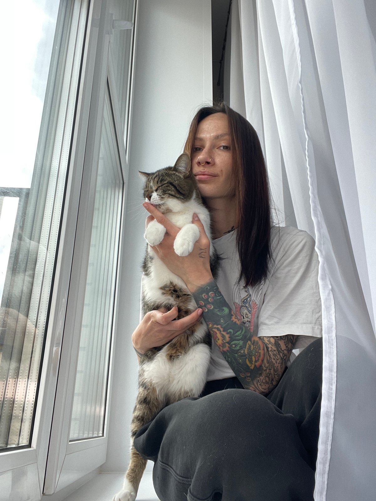 Tattooed woman and tabby cat share quiet morning moments