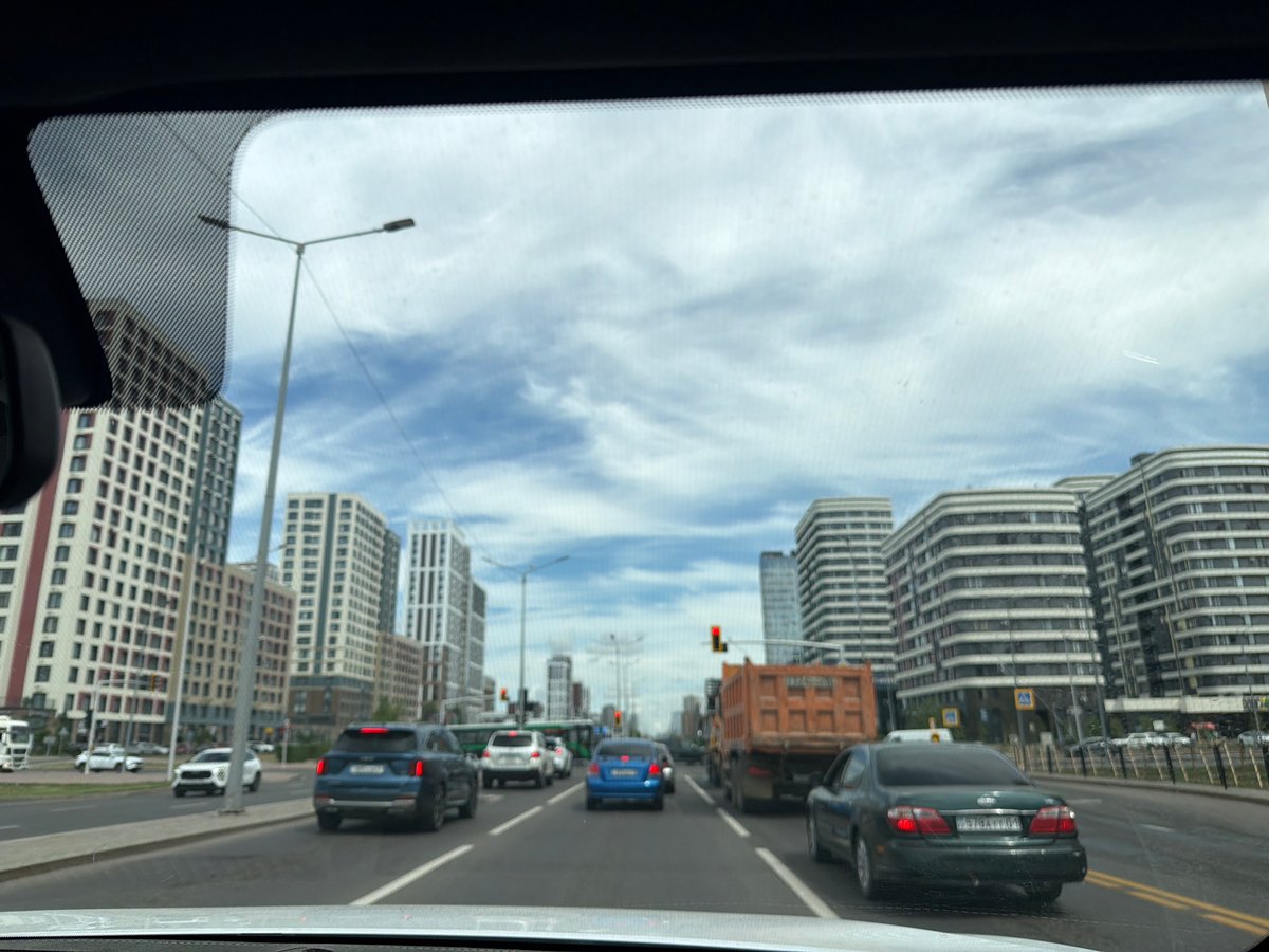 Modern Astana streets: glass towers, traffic, and a fitness club