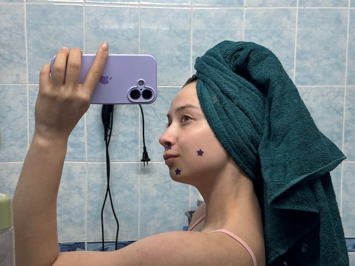 Woman takes selfies with decorative stickers in Russian bathroom