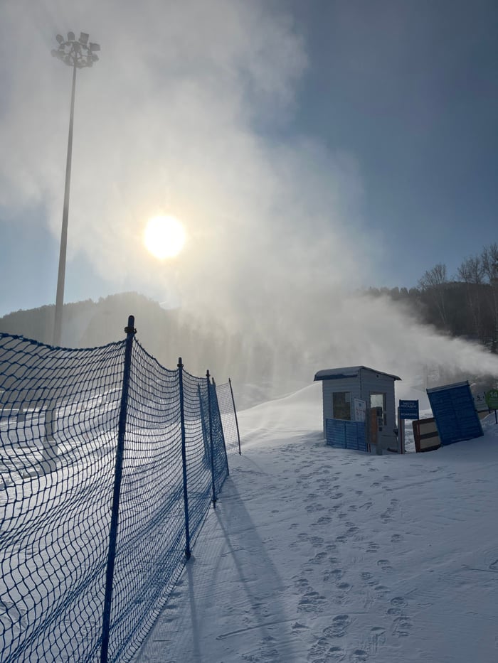 Snow cannons create artificial powder on sunny ski slope