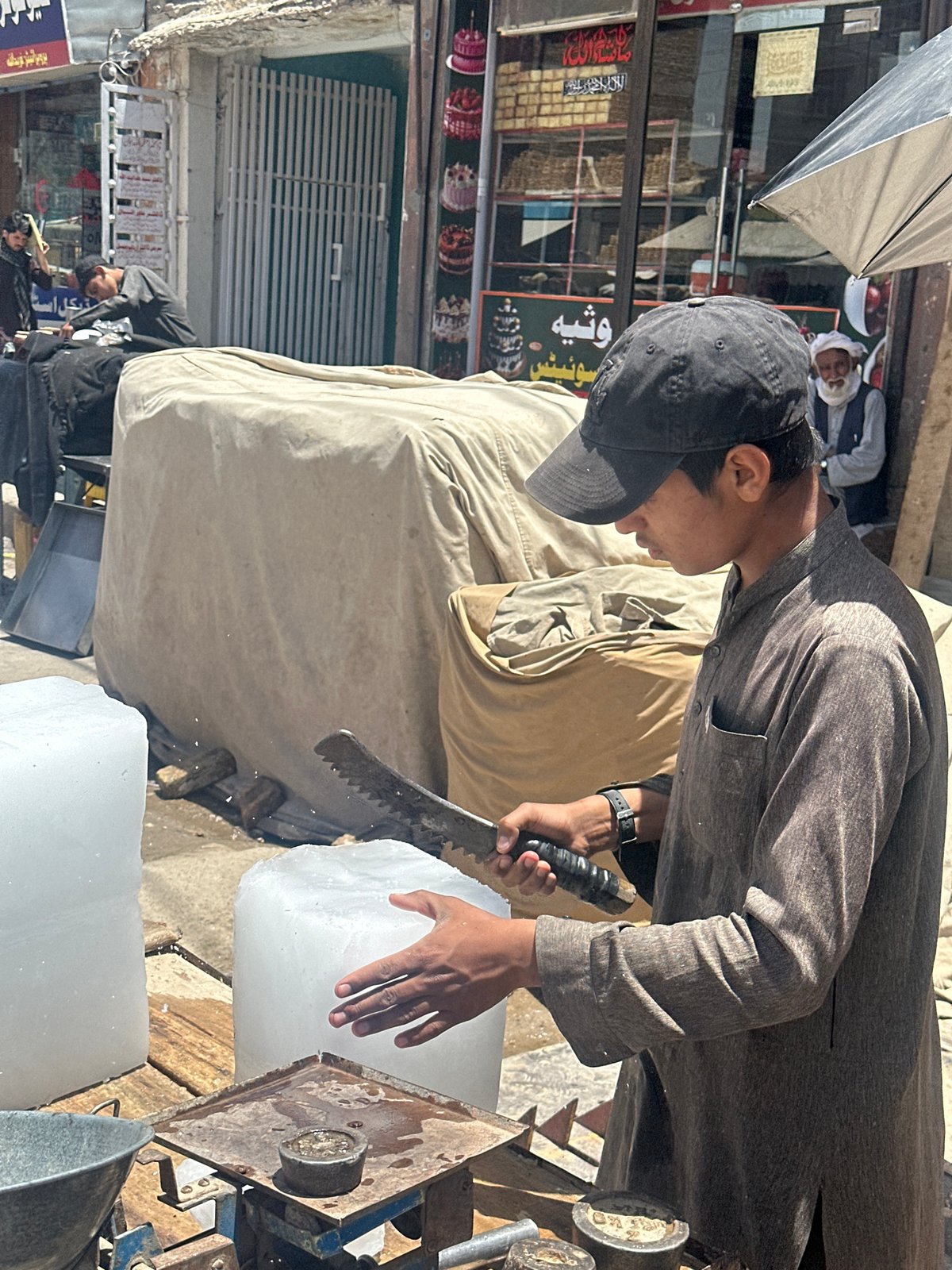 Man cuts ice block on busy Pishin street