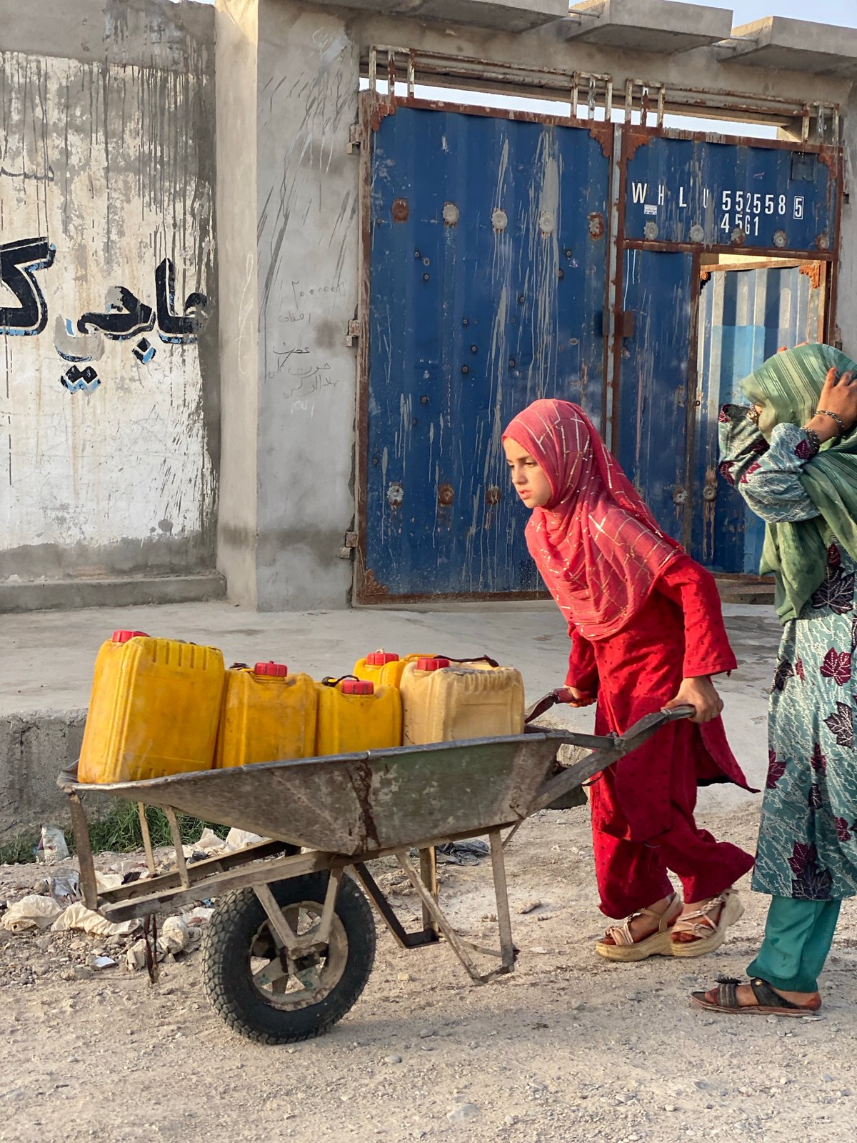 Hauling jerrycans by wheelbarrow through Kandahar streets