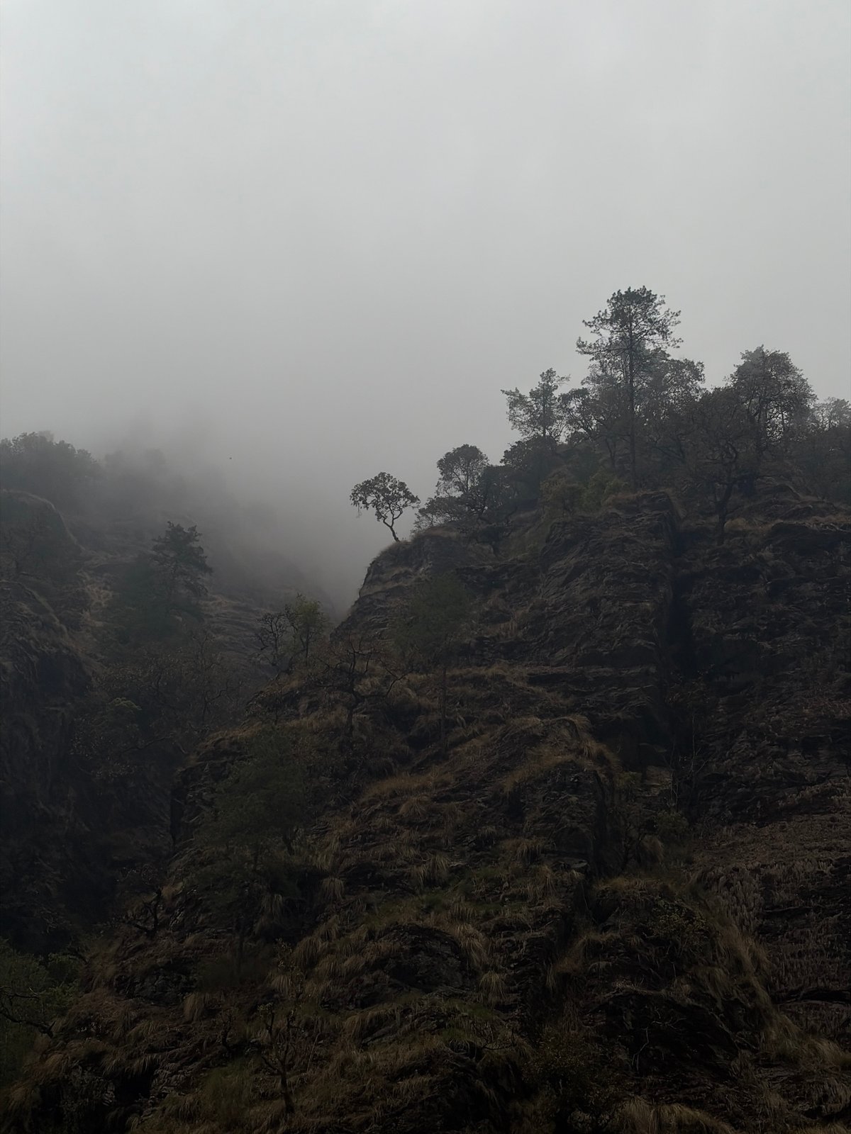 Fog shrouds dramatic cliff face in Dhunche, Nepal