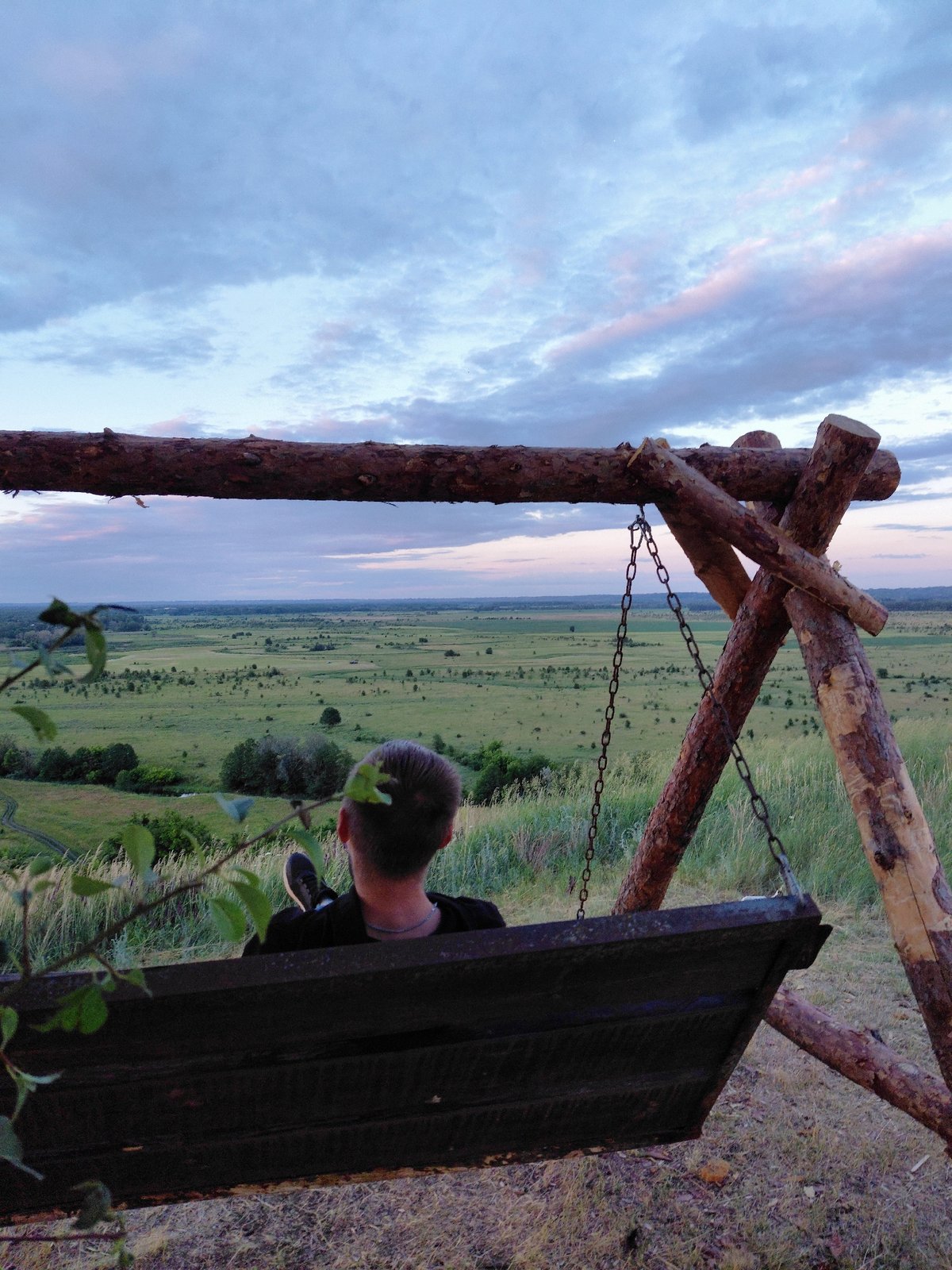 Dusk over open farmland, fields, and a hilltop swing