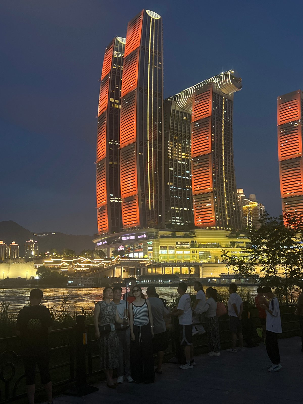 Chongqing riverfront glowing after dark across multiple districts