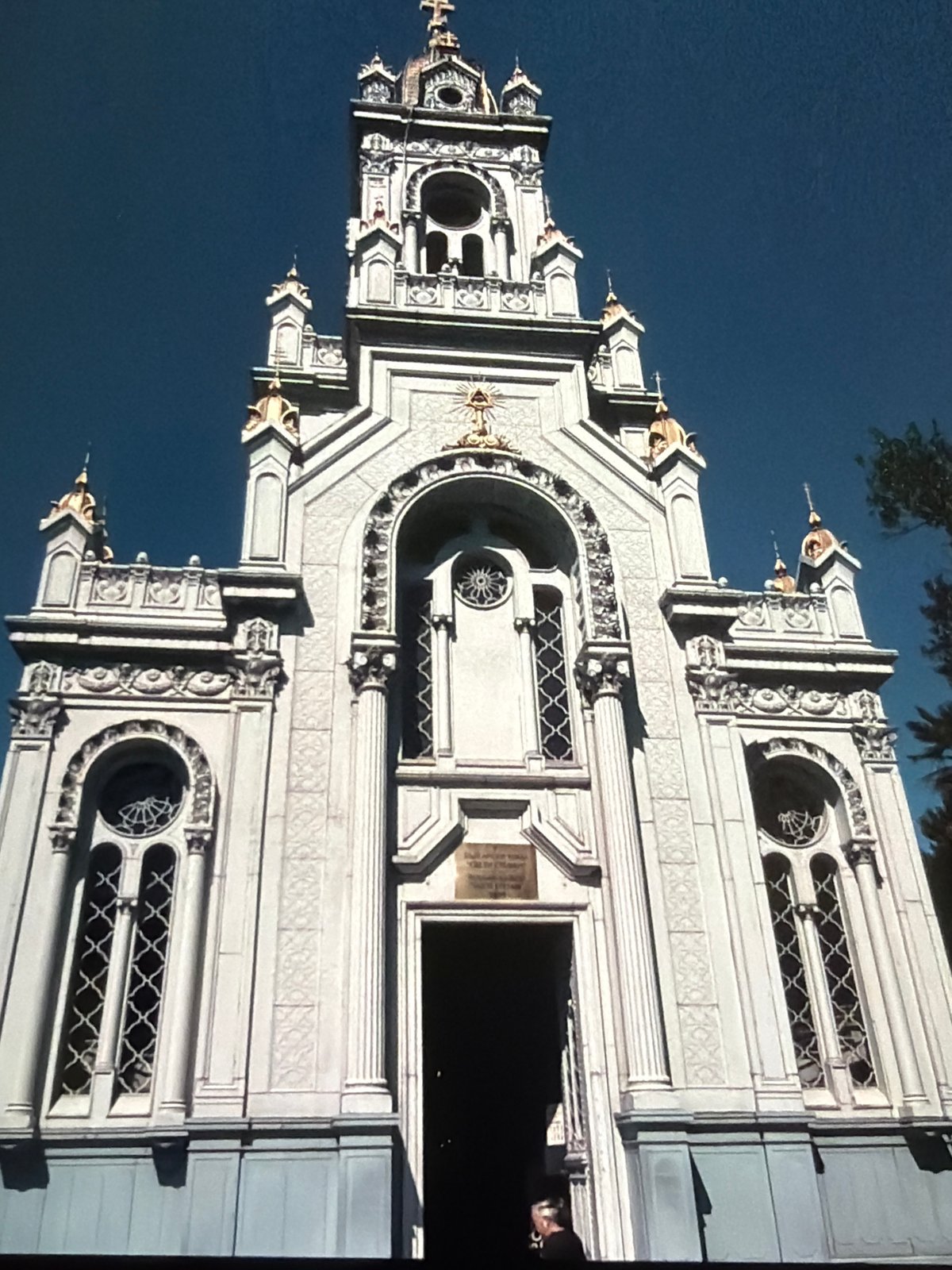 Looking up: ornate stone facade and a contrail-streaked city sky