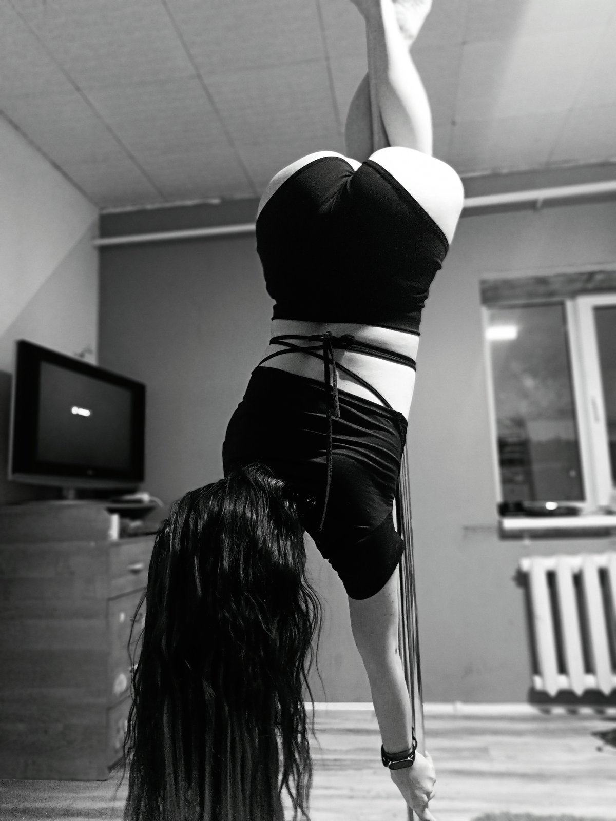 Woman practices pole dancing moves during indoor training session