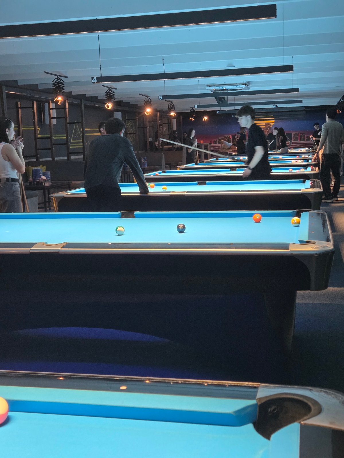 Pool hall buzzing with evening billiards games and spectators