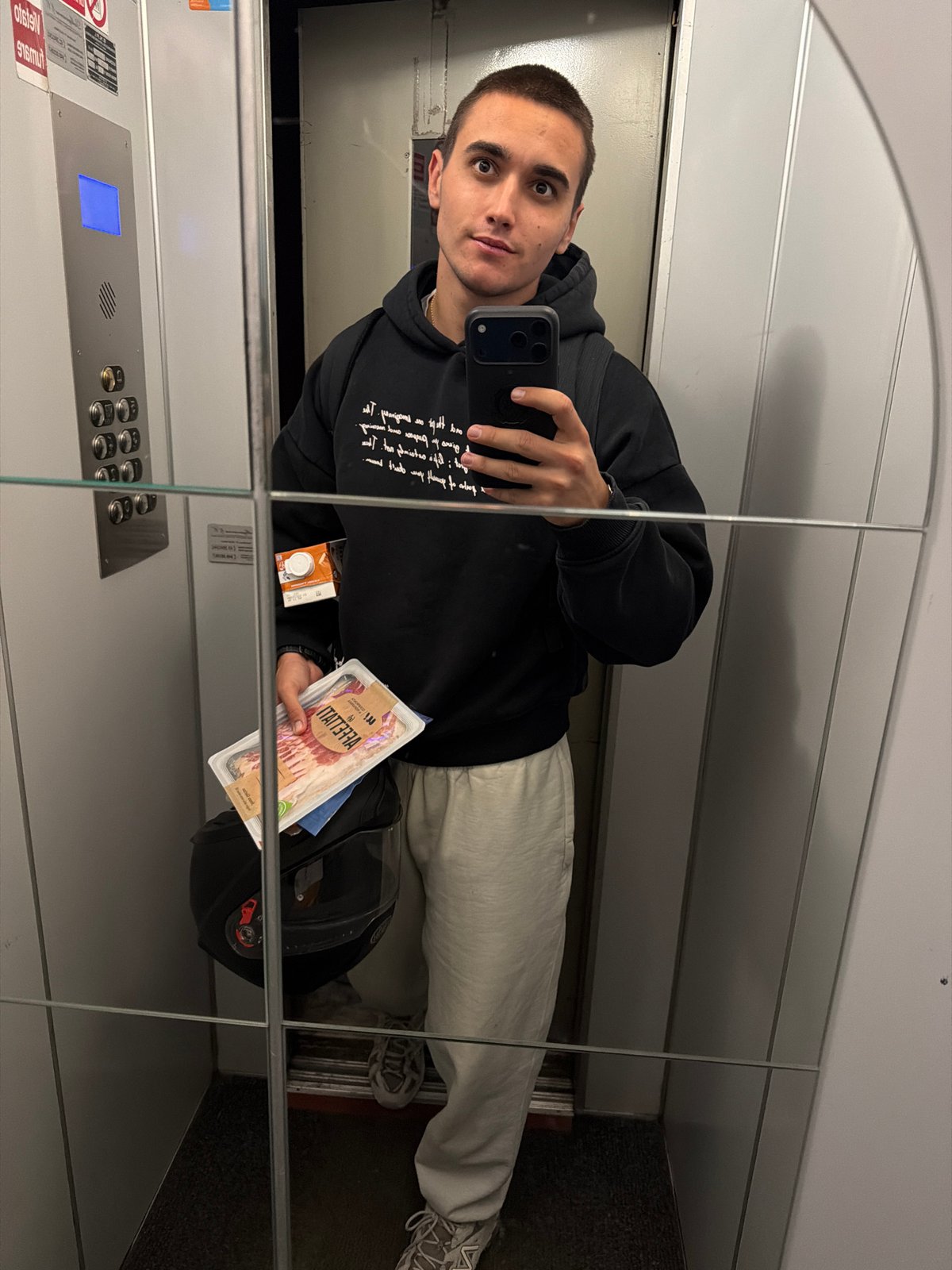 Man takes elevator selfie while holding bacon package in Milan